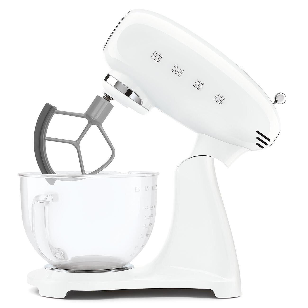 Ein weißer Smeg-Küchenmixer mit einem grauen Schläger und einer Glasschüssel. Der Mixer steht auf einer weißen Oberfläche.