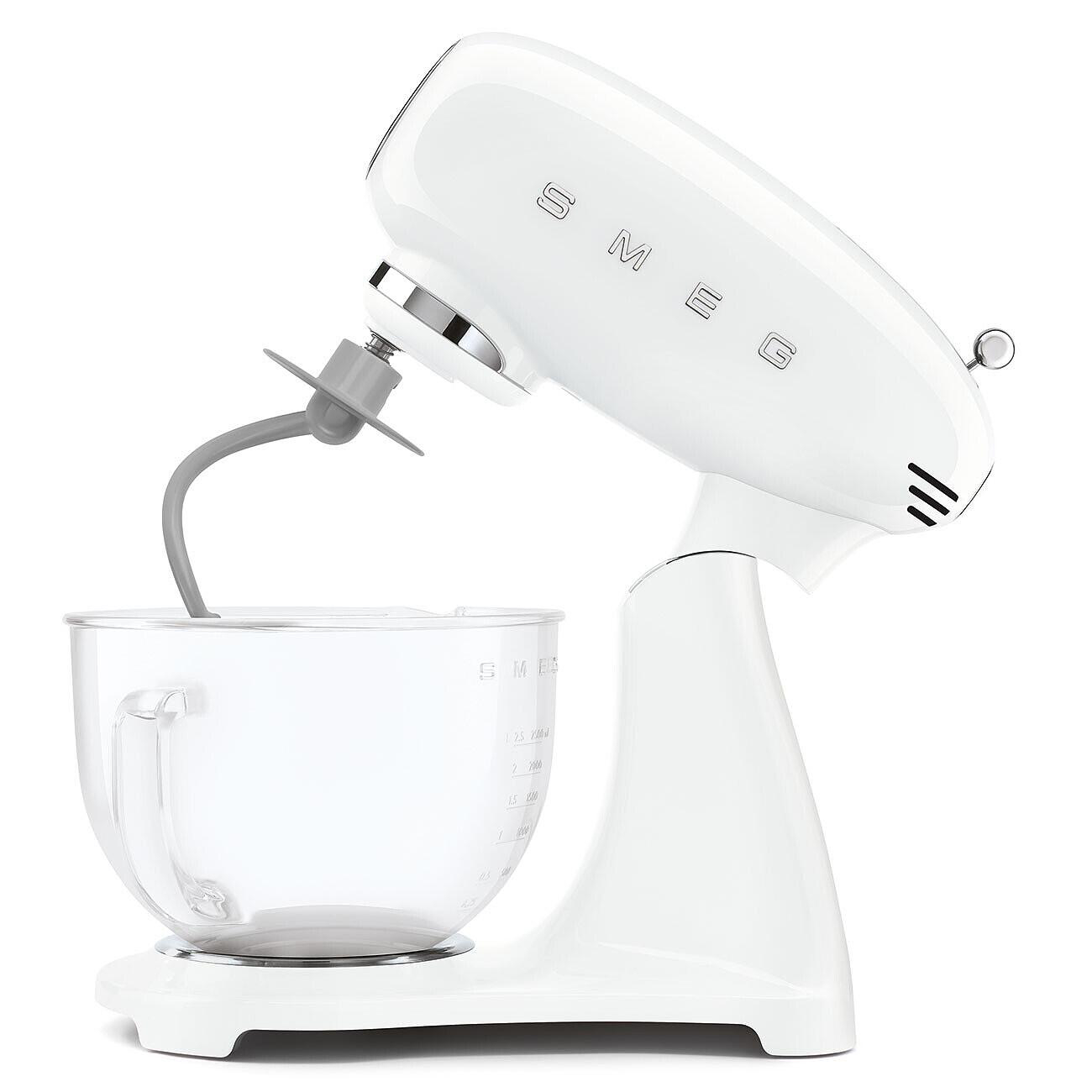 Ein weißer SMEG-Küchenmixer mit einer transparenten Schüssel wird gezeigt. Der Arm des Mixers ist angehoben, und ein grauer Aufsatz befindet sich in der Schüssel.