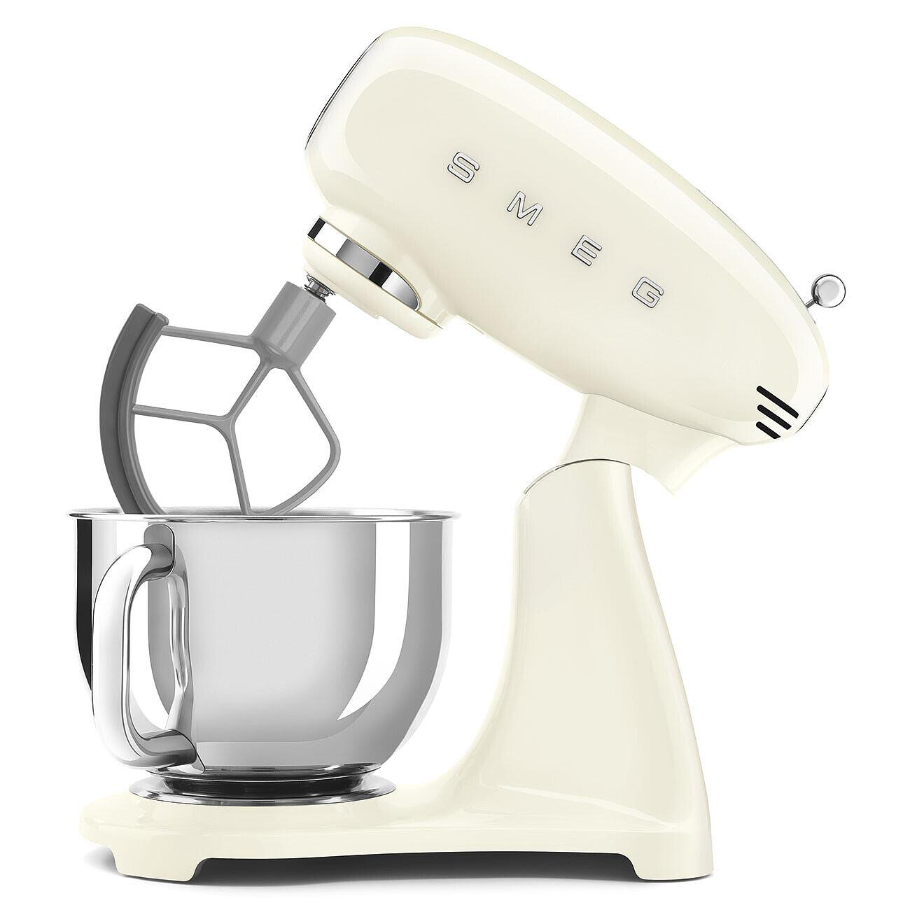Cremefarbener SMEG-Küchenmixer. Beinhaltet eine Edelstahlschüssel und einen grauen Mixaufsatz. Der Mixer steht auf einer weißen Oberfläche.