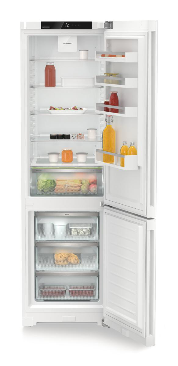 Geöffneter Kühlschrank gefüllt mit Lebensmitteln: Gläser, Saft, Gemüse und Behälter. Weißer Innenraum. Untere Schublade offen.