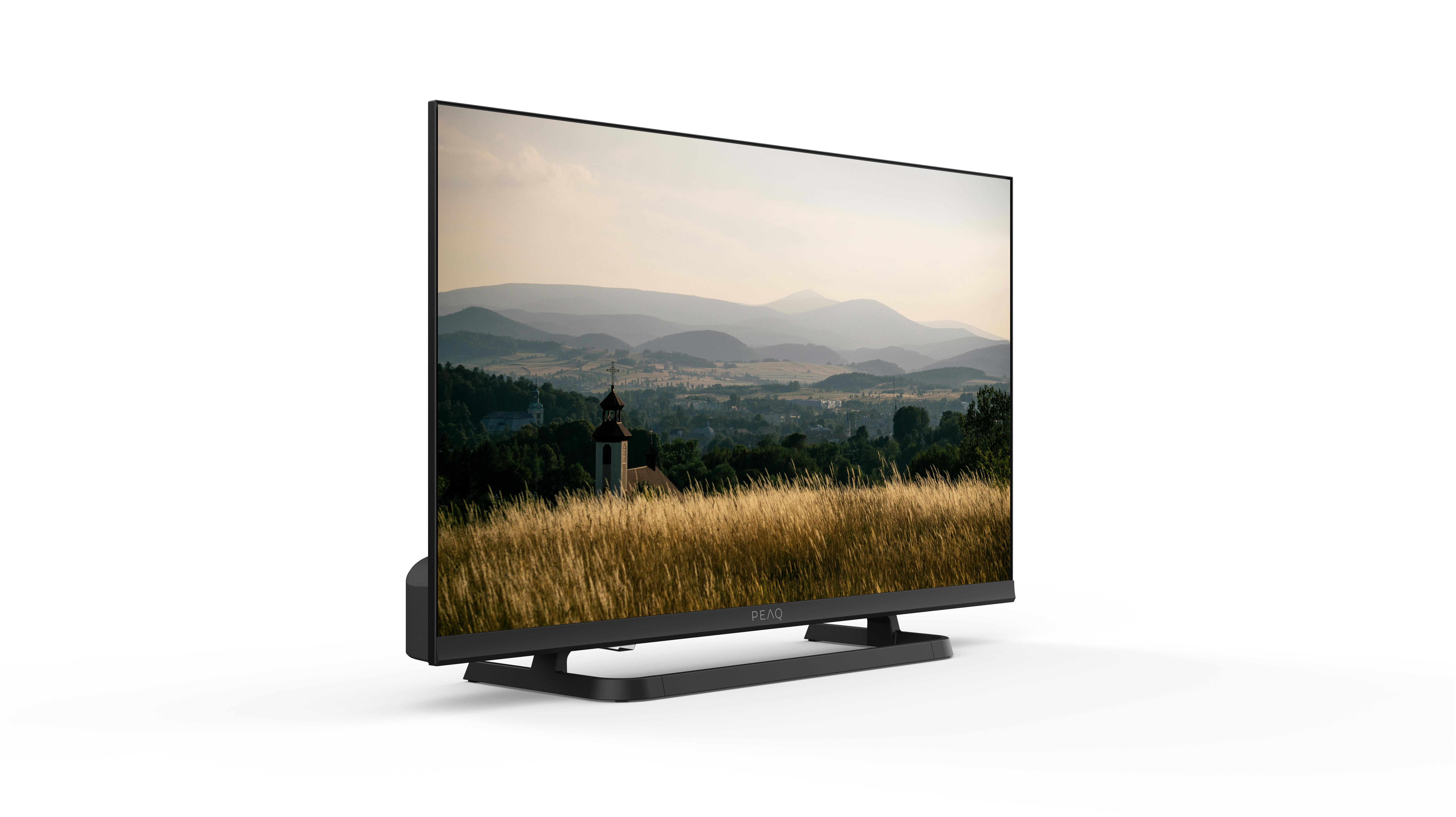 Ein schwarzer Fernseher zeigt eine Landschaft mit Kirche und Bergen. Der Fernseher steht auf weißem Untergrund.