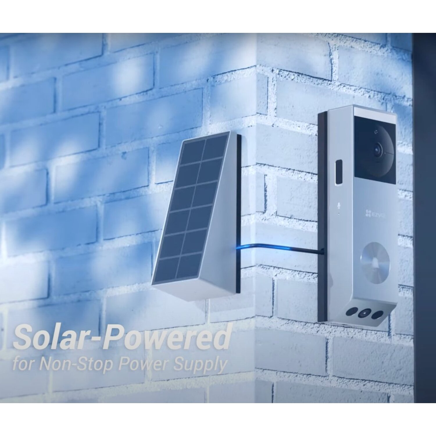 A solar panel and a security camera are mounted on a white brick wall, connected by a blue wire.
