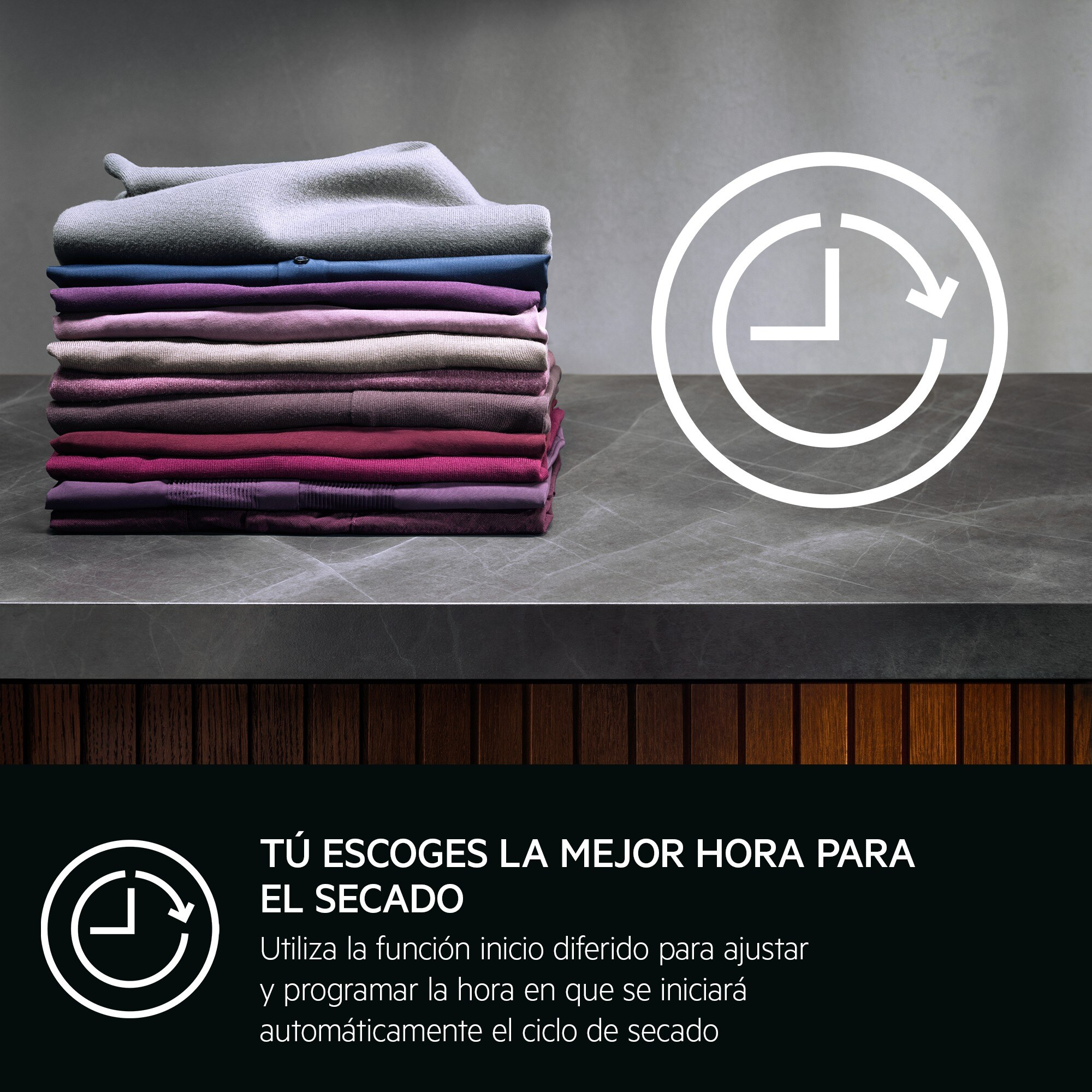 Pila de ropa doblada de varios colores sobre una encimera, con un icono de reloj. Texto: Tú eliges la mejor hora para el secado.