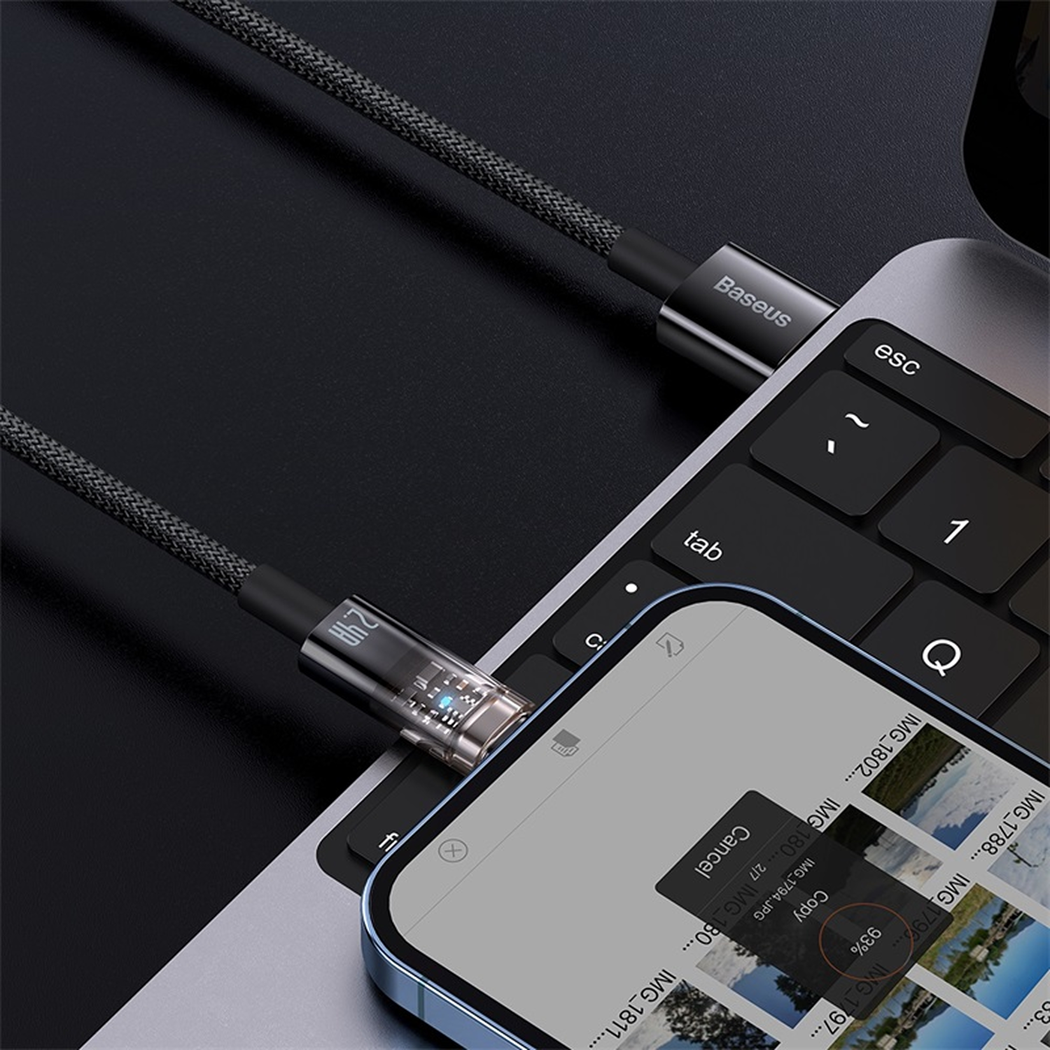 Un teléfono conectado a una laptop por cable. El teléfono muestra una copia de archivo al 93%. Detalles del teclado y cable visibles.