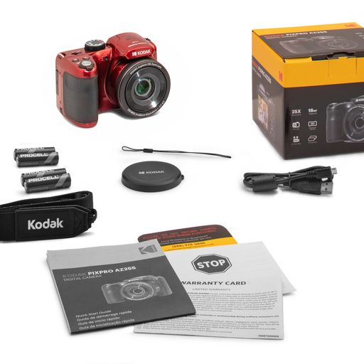 Kırmızı Kodak kamera, piller, kılavuzlar ve bir kutu gibi aksesuarlarla. Tüm nesneler beyaz bir yüzey üzerinde.