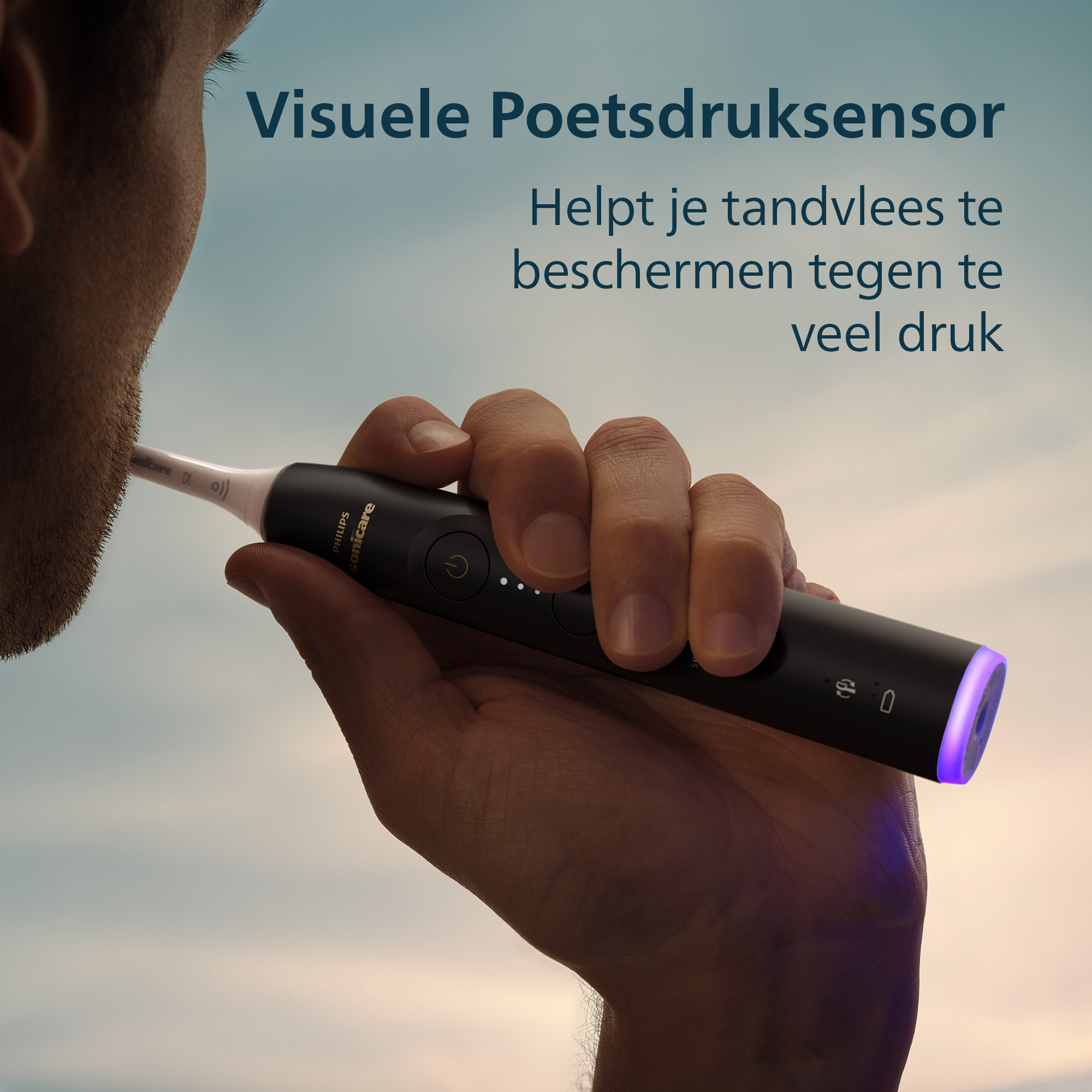 A person holds a black Philips Sonicare toothbrush. Text in Dutch says the toothbrush helps protect gums from pressure.
