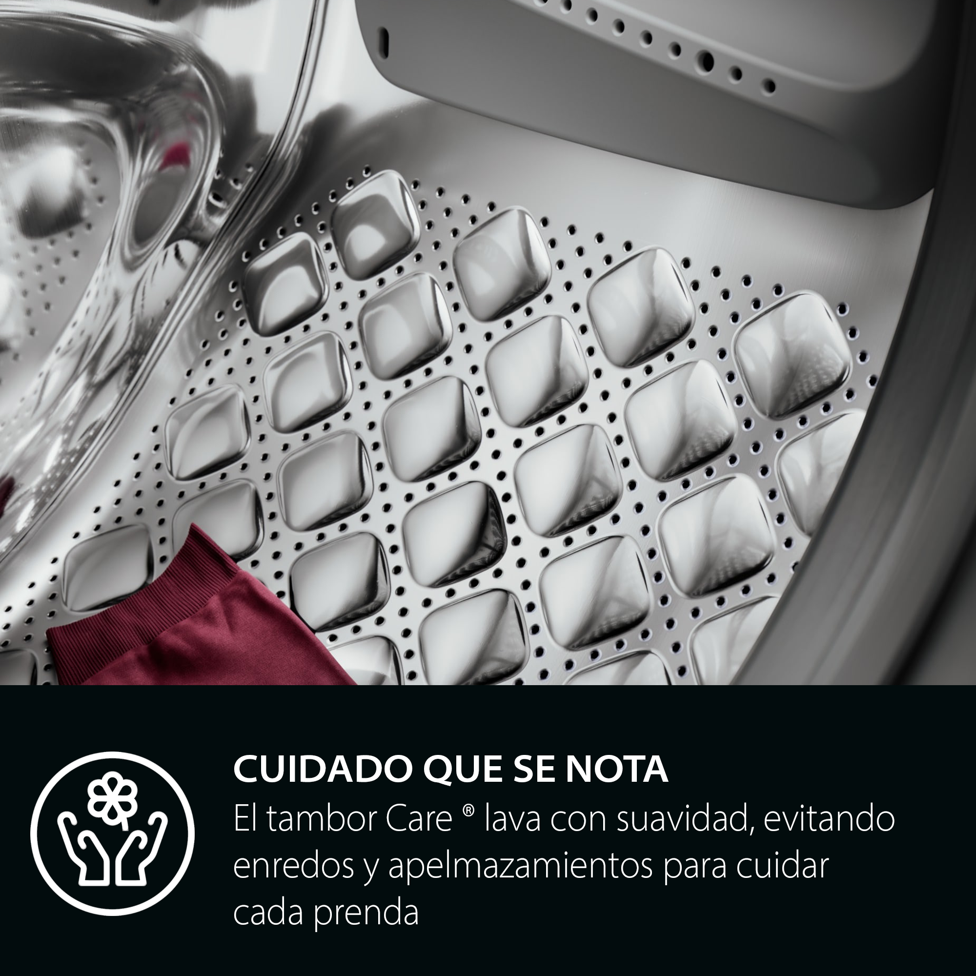 Interior del tambor de la lavadora con una prenda roja. El tambor es metálico con hendiduras cuadradas, texto en la parte inferior.
