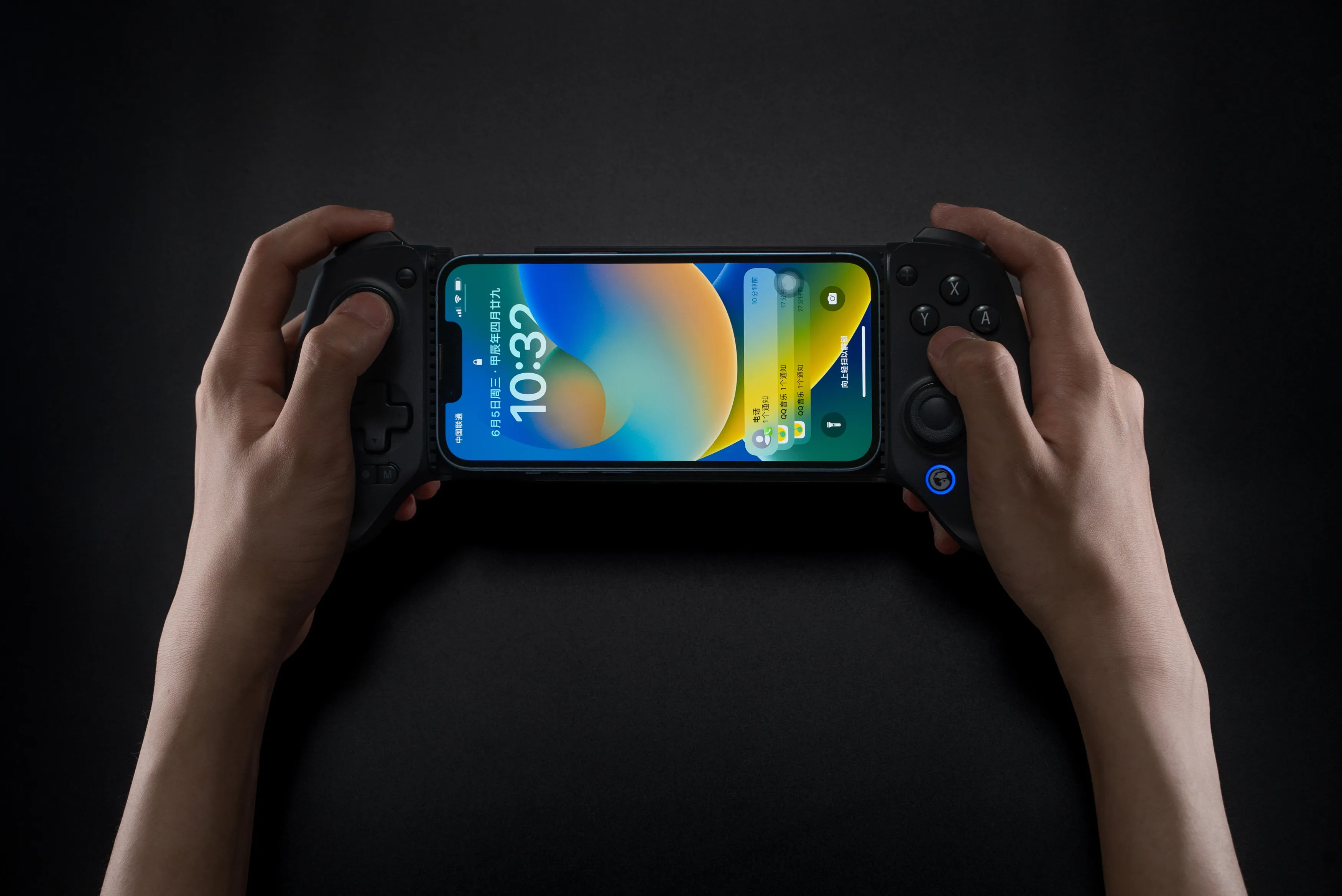 Hände halten ein Smartphone in einem Gamecontroller. Das Telefon zeigt die Uhrzeit und Apps mit blauem und gelbem Hintergrund.