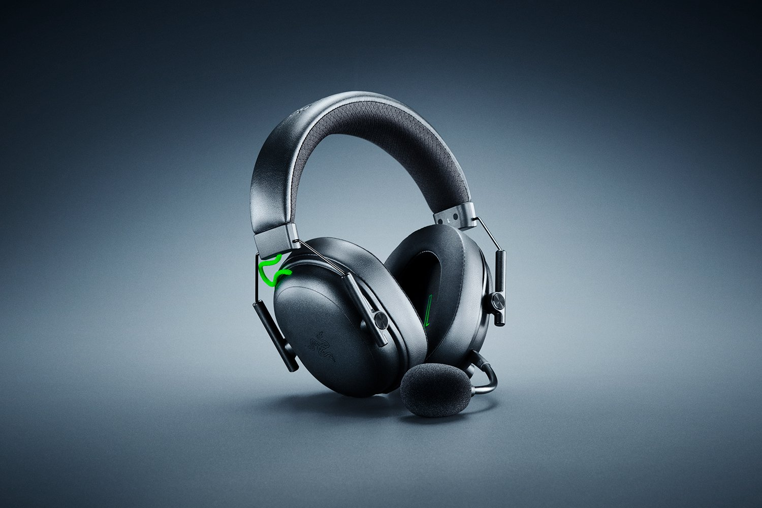 Schwarzes Gaming-Headset auf grauer Oberfläche mit Mikrofon. Grüne Akzente am Headset. Der Hintergrund ist grau.