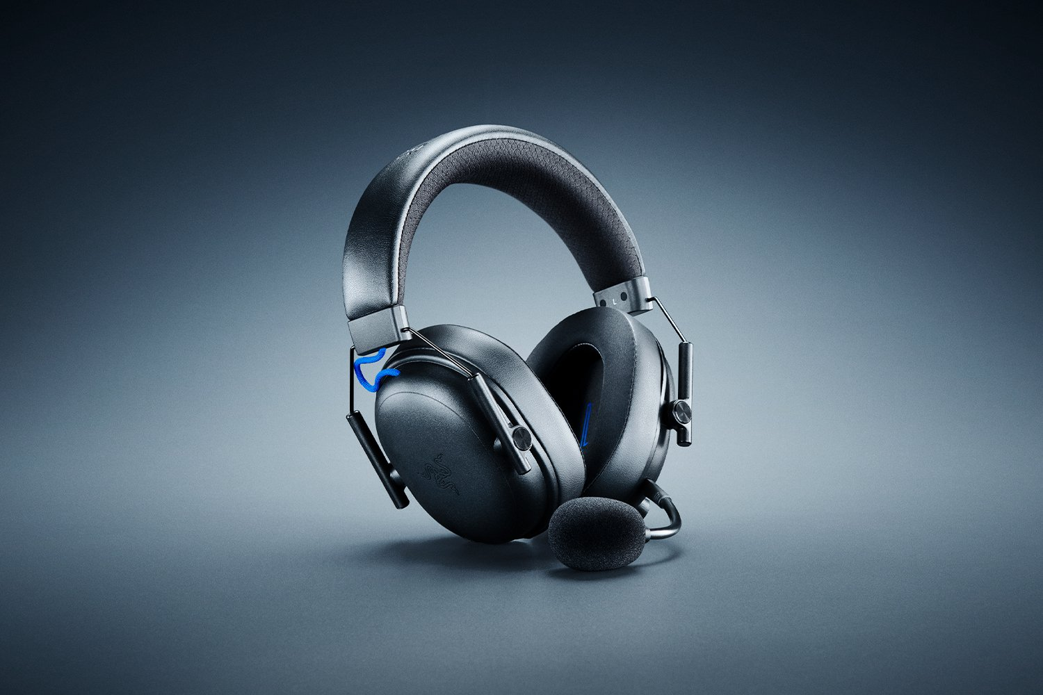 Schwarzes Gaming-Headset auf grauer Oberfläche, mit Mikrofon. Das Headset hat blaue Akzente. Der Hintergrund ist ein grauer Farbverlauf.