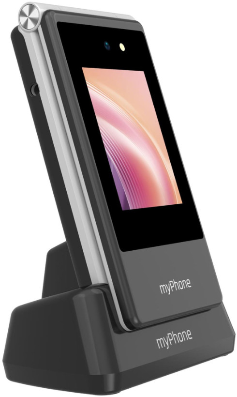 Szary telefon myPhone spoczywa na czarnej stacji ładującej. Ekran telefonu wyświetla kolorowy obraz. Telefon ma aparat.