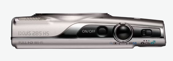 Srebrny aparat Canon IXUS 285 HS. Posiada przycisk włączania/wyłączania, pokrętło i funkcje Wi-Fi. Aparat znajduje się na białym tle.