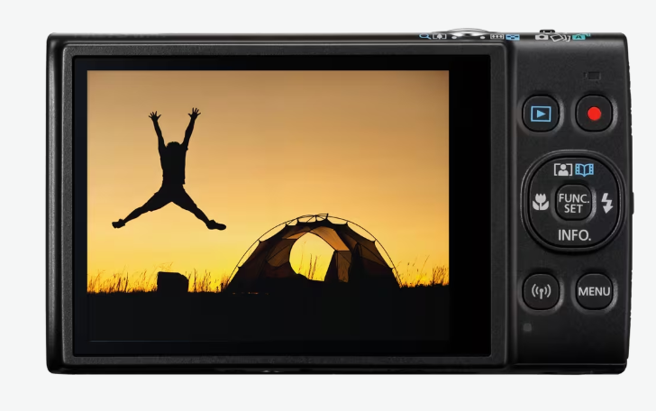 Ekran aparatu pokazuje sylwetkę osoby skaczącej w pobliżu namiotu z zachodem słońca w tle. Aparat jest czarny.