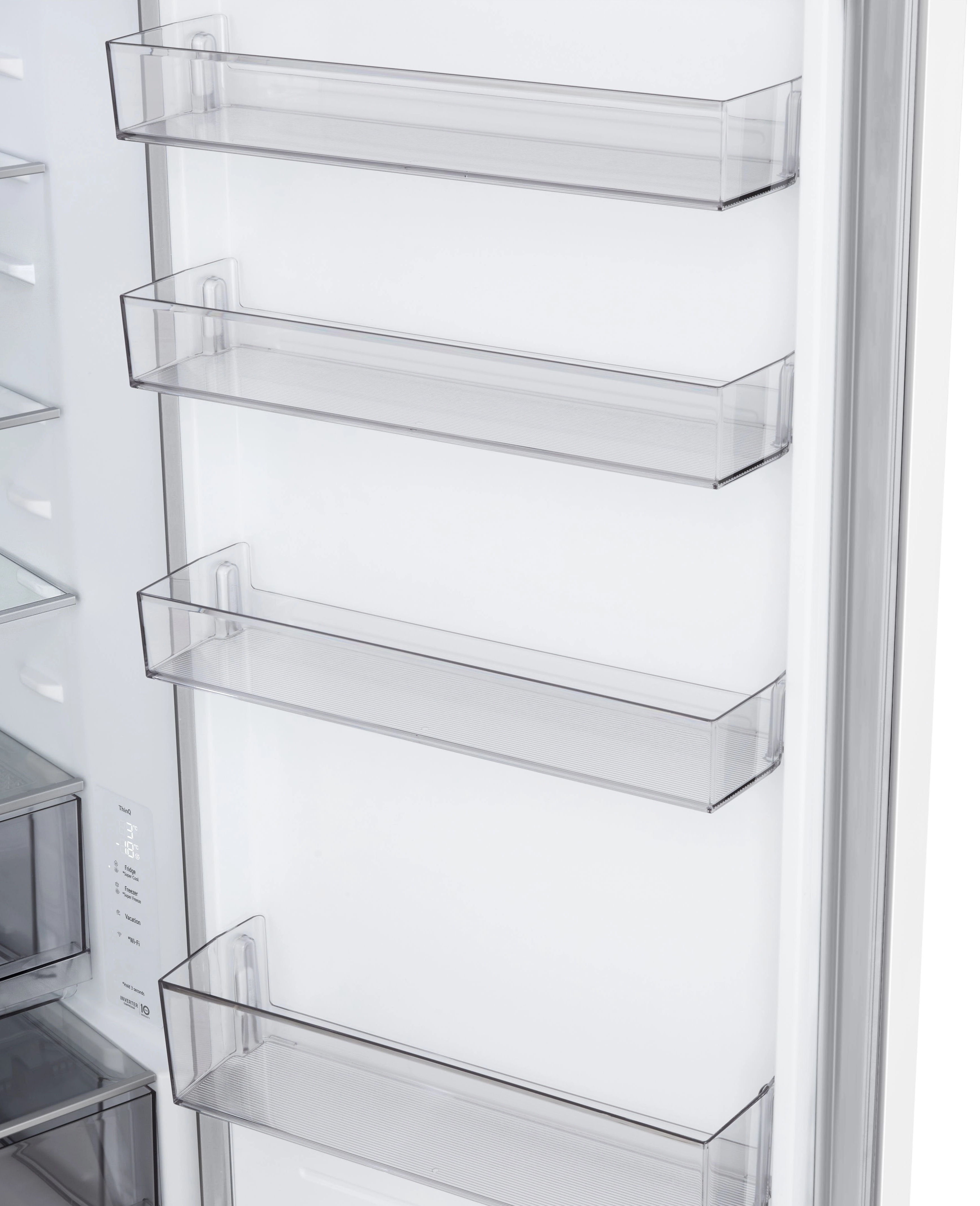 Wnętrze otwartej lodówki z przezroczystymi półkami. Białe ściany, wyświetlacz cyfrowy i srebrna rama widoczne.
