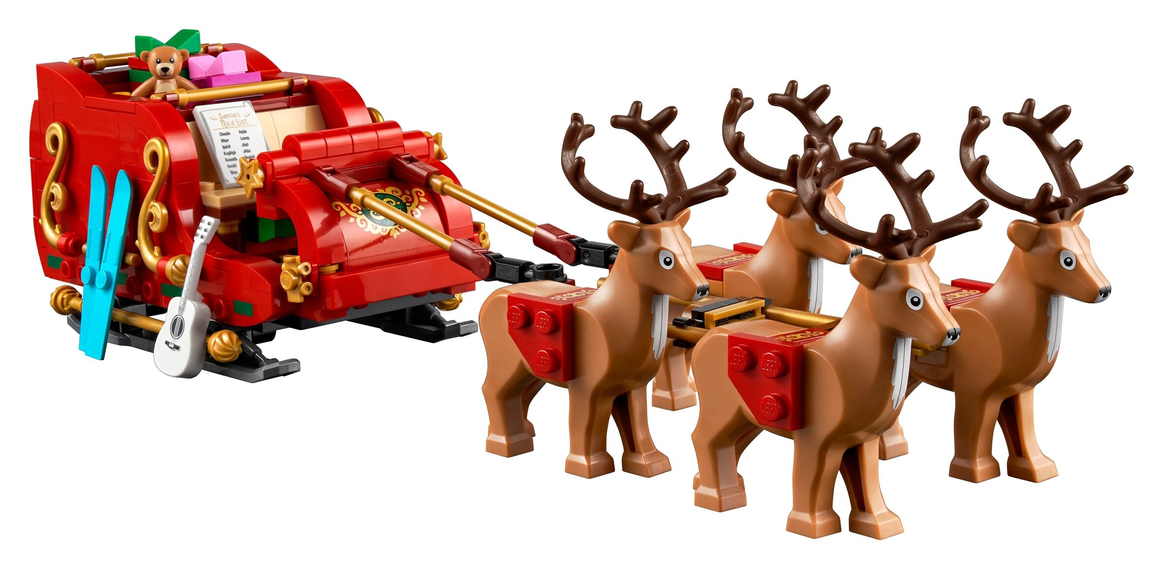 Scena świąteczna Lego z saniami Świętego Mikołaja ciągniętymi przez renifery. Sanie są czerwone, z nartami, gitarą i misiem.