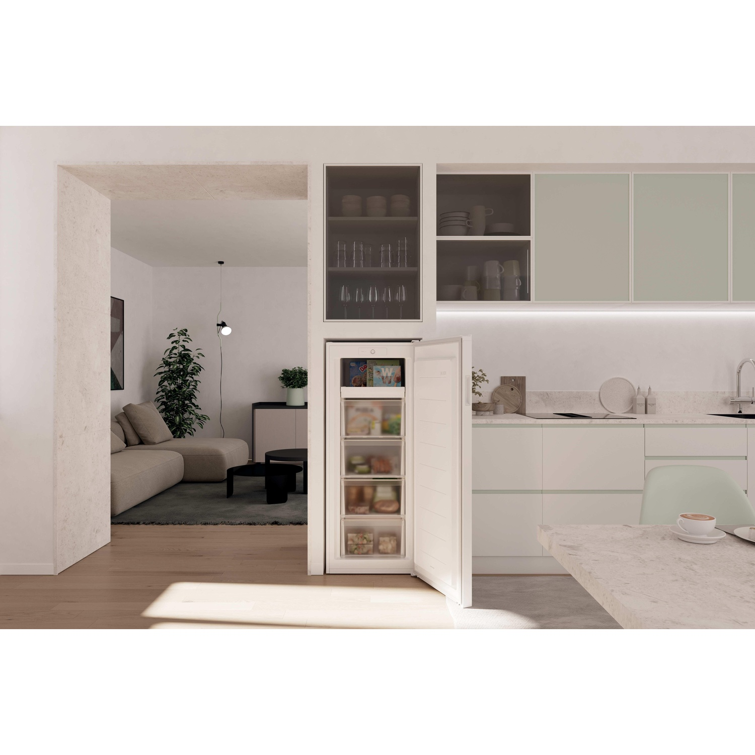 Freezer aperto in cucina. Soggiorno visibile attraverso la porta. Mobili e tavolo dai colori chiari. Tazza di caffè sul tavolo.