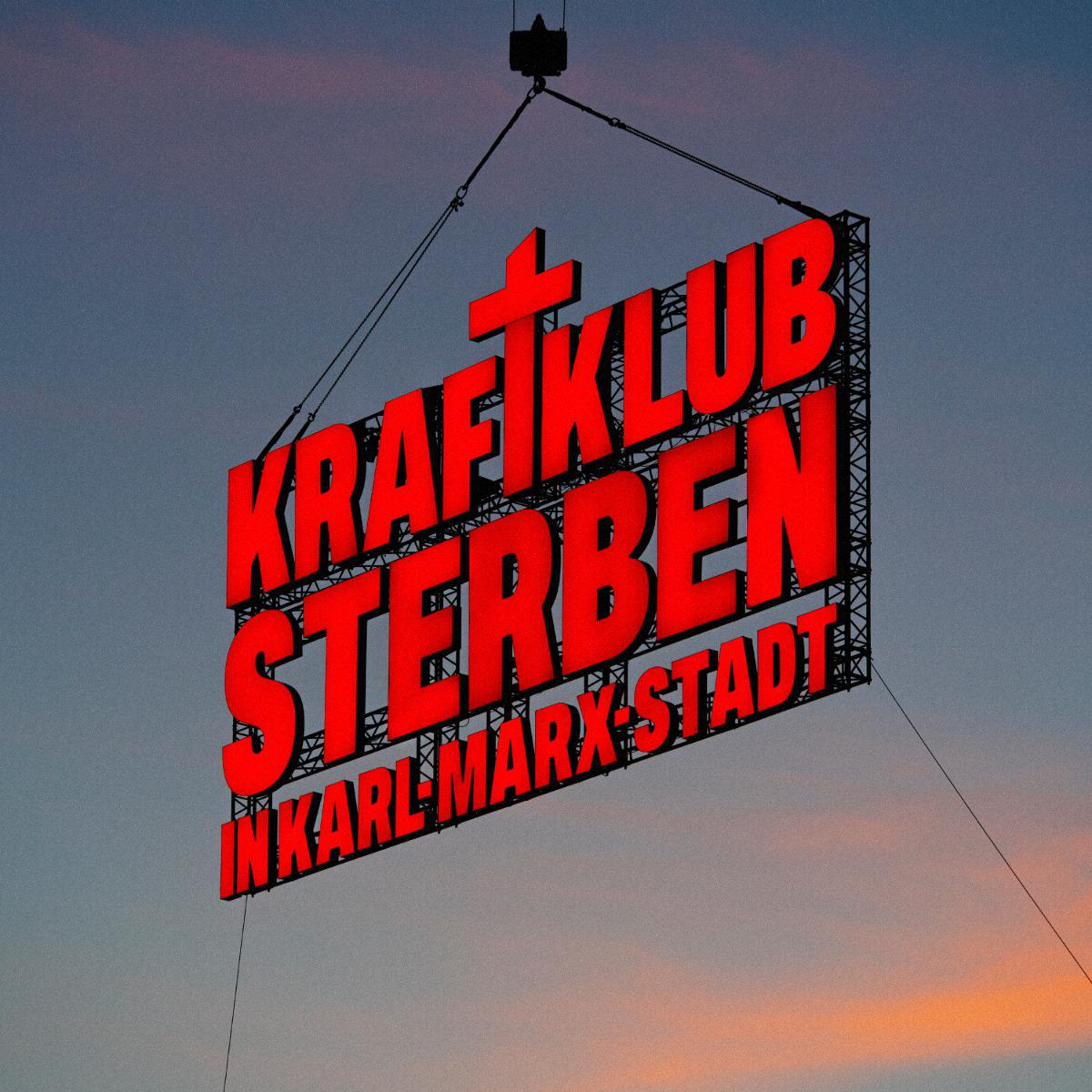 Großes rotes Neon-Schild: KRAFTKLUB STERBEN IN KARL-MARX-STADT, hängt vor dem Abendhimmel. Ein Kreuz über dem 'K'.