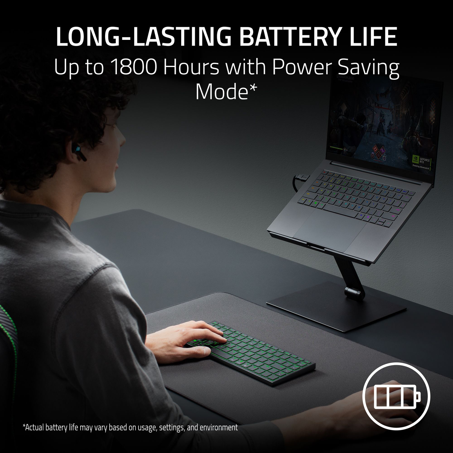 A person using a laptop on a stand with a keyboard. The screen shows a game, and the text highlights long-lasting battery life.