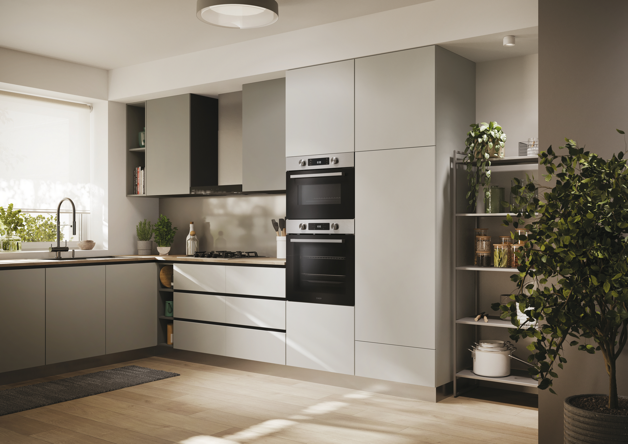 Cocina moderna con gabinetes gris claro, piso de madera, horno empotrado y una planta de interior grande.