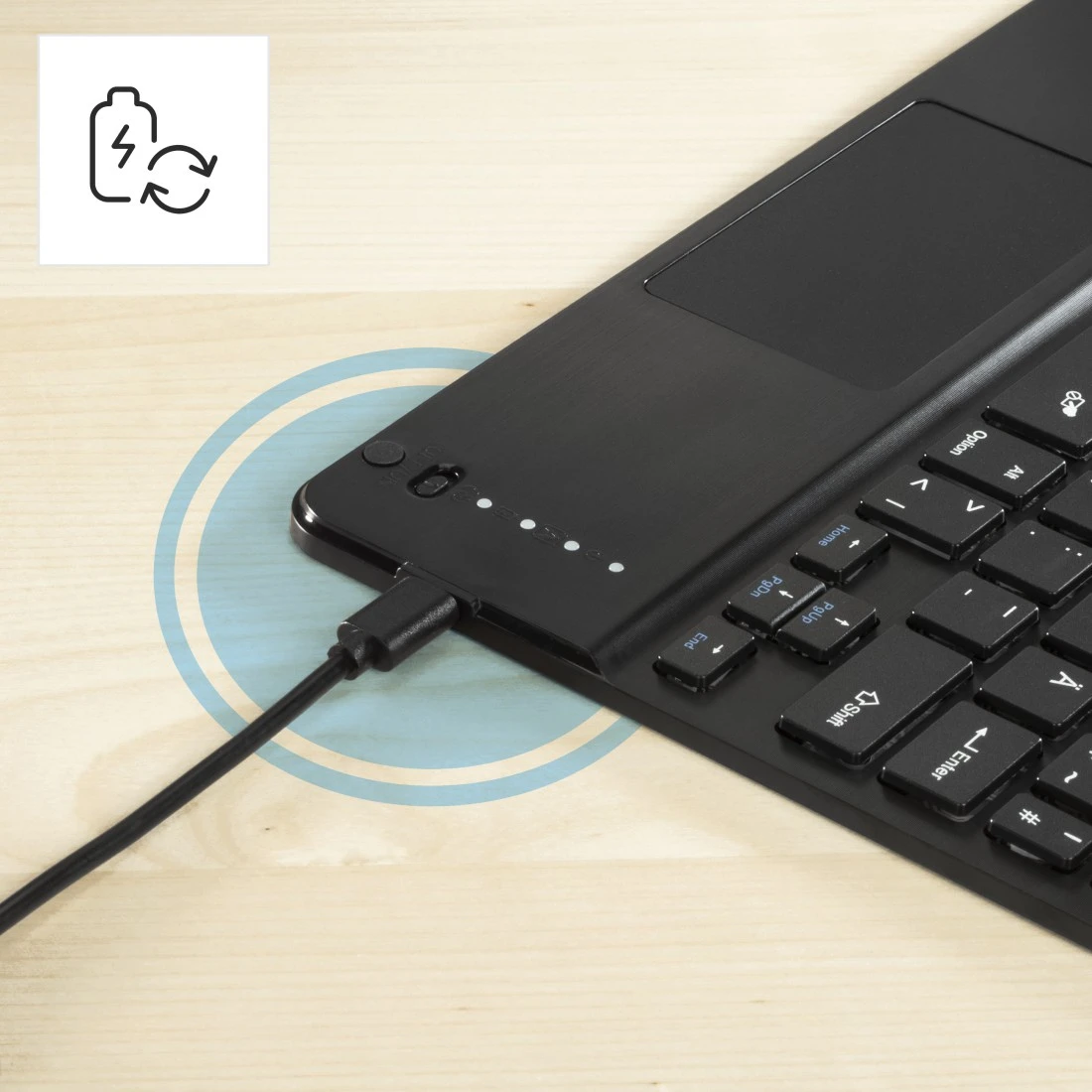 Schwarze Tastatur mit Touchpad, Ladekabel eingesteckt. Akkusymbol in der Ecke. Ladeanzeige-Leuchten sind an.