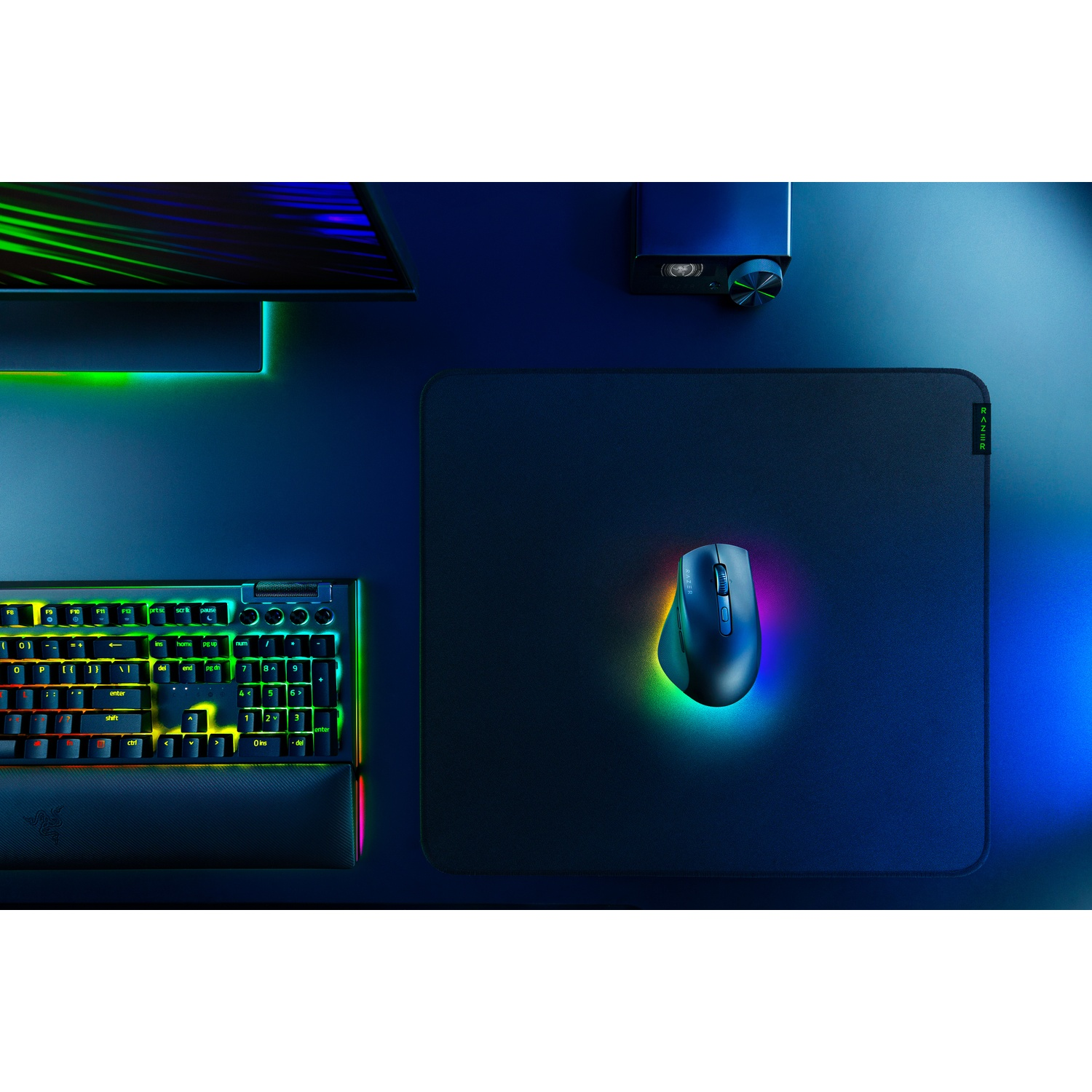 Une configuration de jeu avec un clavier, une souris et un tapis de souris. L'ensemble est sur une surface sombre, éclairé par un éclairage RVB coloré.