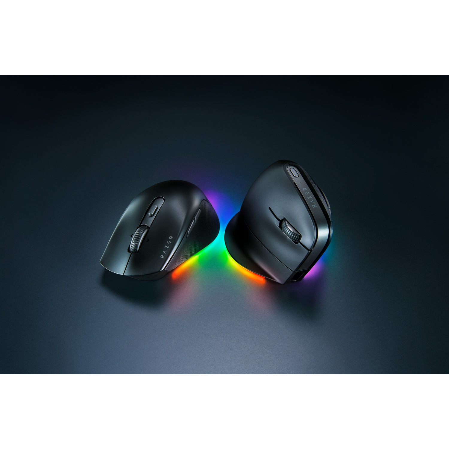Deux souris ergonomiques Razer noires avec lumières arc-en-ciel. Les souris sont sur une surface sombre, éclairées par le bas avec des teintes colorées.