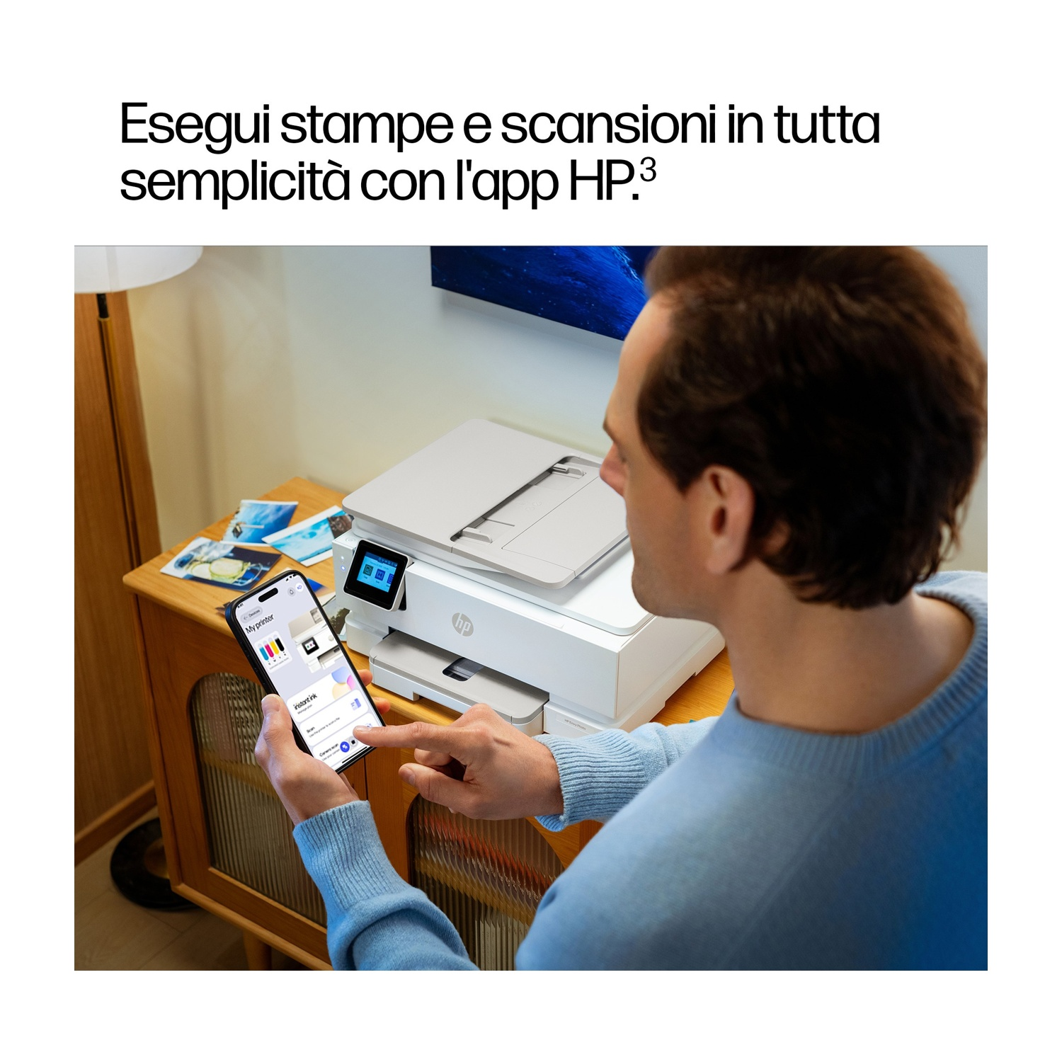 Un uomo usa un'app per controllare una stampante HP bianca. Lo schermo mostra le opzioni della stampante. La stampante è su un mobile di legno.