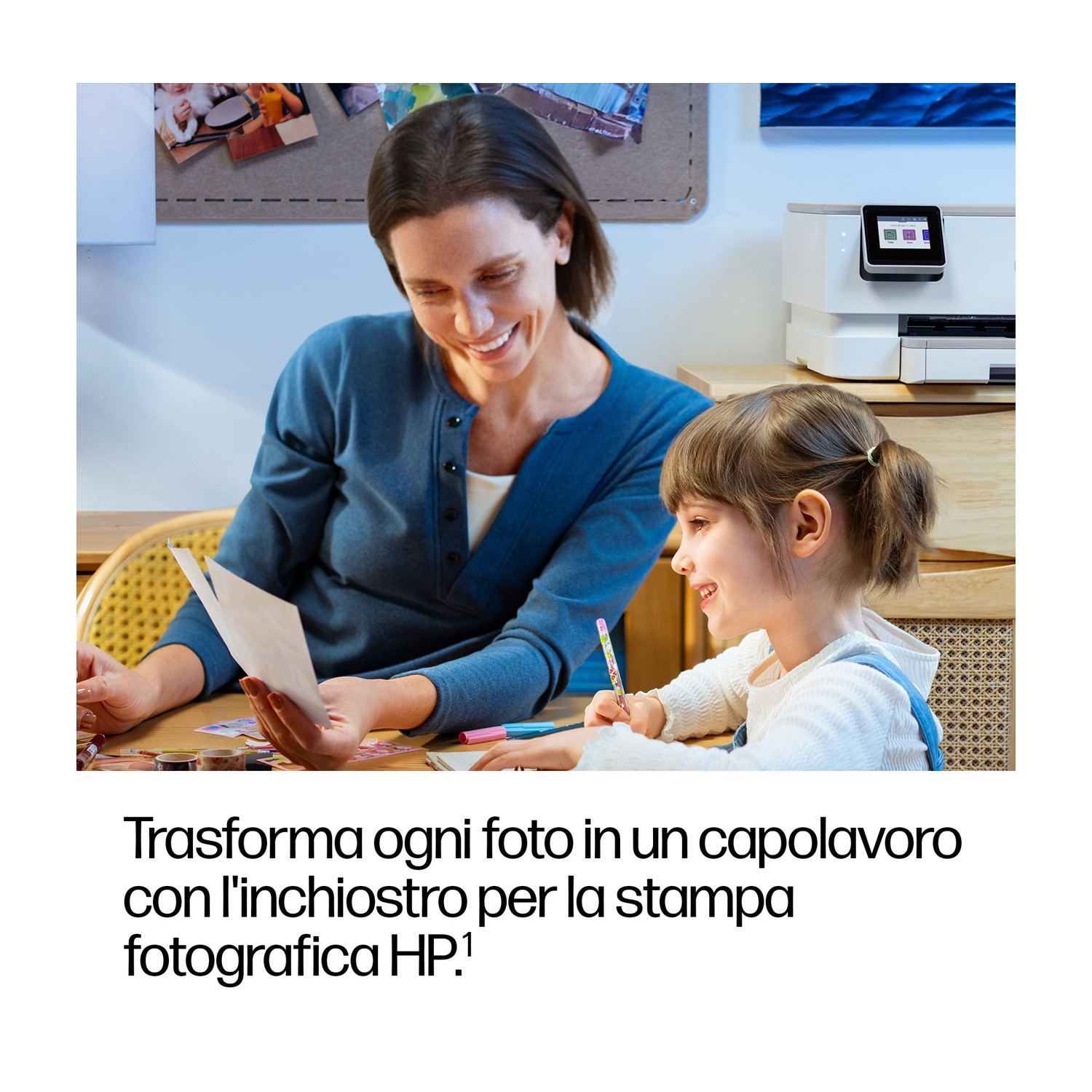 Una donna e una bambina guardano delle foto. C'è una stampante dietro di loro. Stanno sorridendo. Una matita e delle penne colorate sono sul tavolo.
