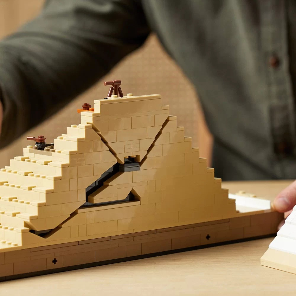 Model Lego piramidy jest montowany. Jest beżowy z detalami wnętrza. Osoba w zielonej koszuli jest w tle.