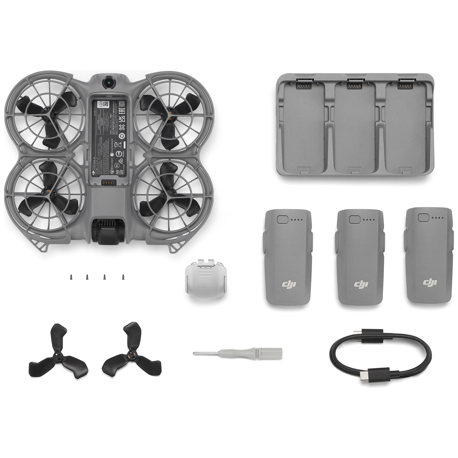 Drone en accessoires. Drone in bovenaanzicht, propellers, oplaadetui, batterijen, schroevendraaier en kabel, alles op witte achtergrond.