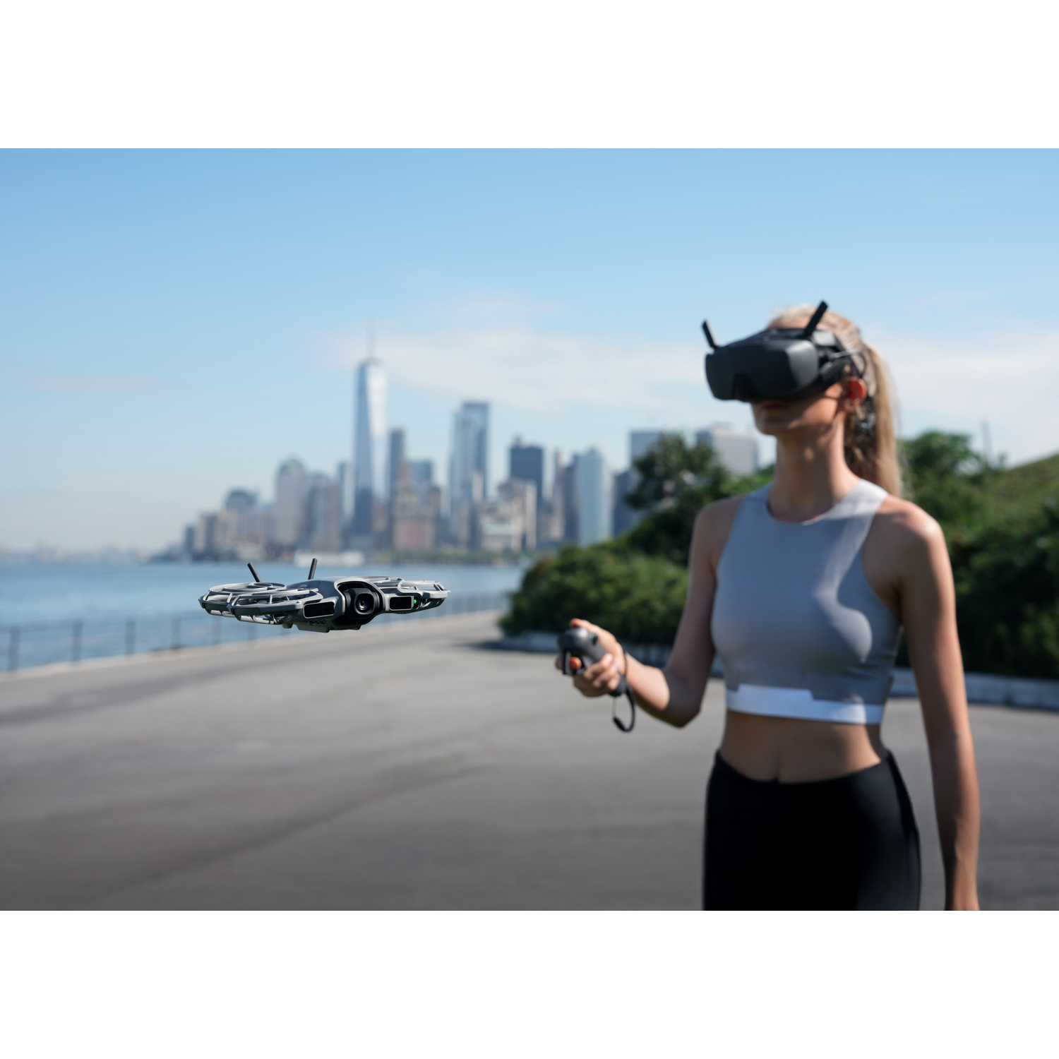 Een vrouw met een VR-bril bestuurt een drone. De drone zweeft voor haar. De skyline van New York staat op de achtergrond.