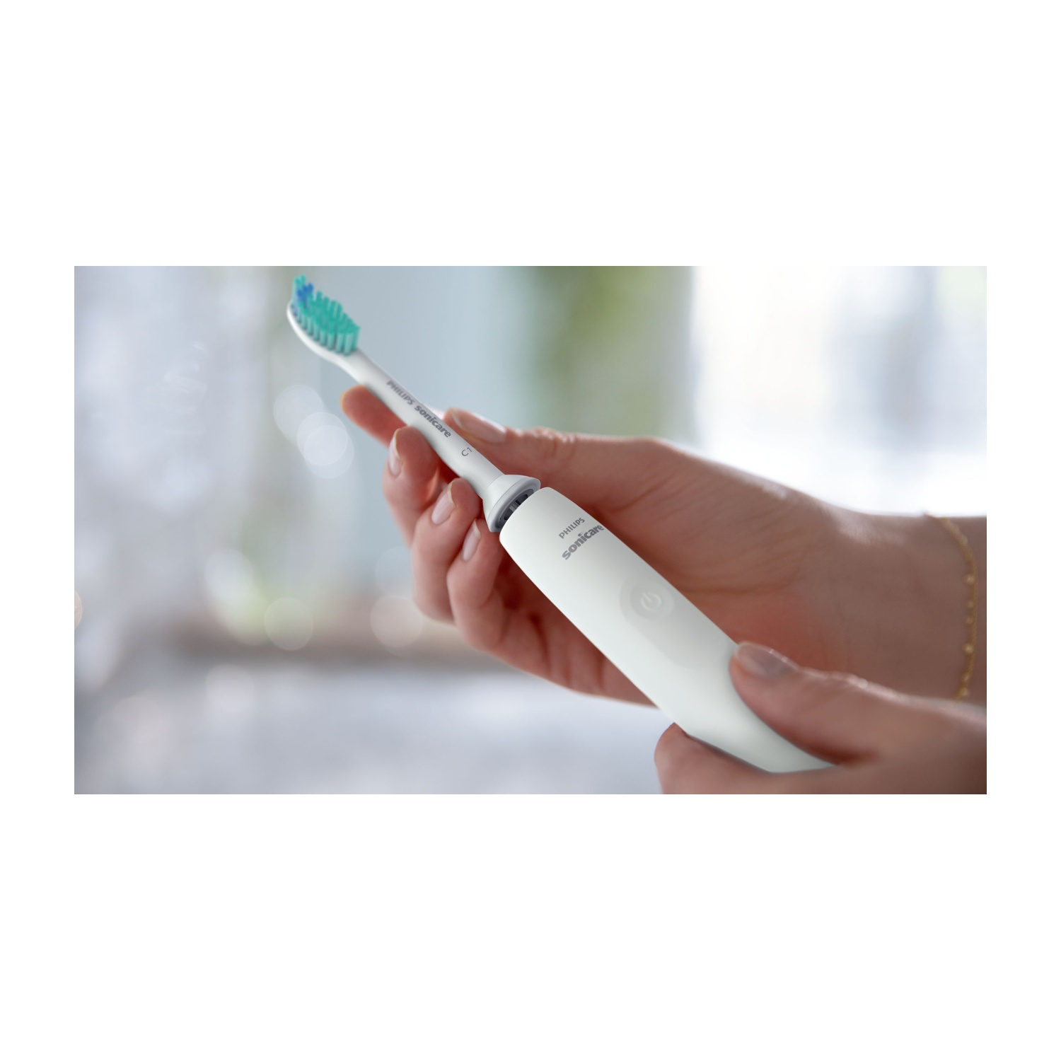 Uno spazzolino elettrico Philips Sonicare bianco è tenuto in mano. La testina ha setole verdi e blu.