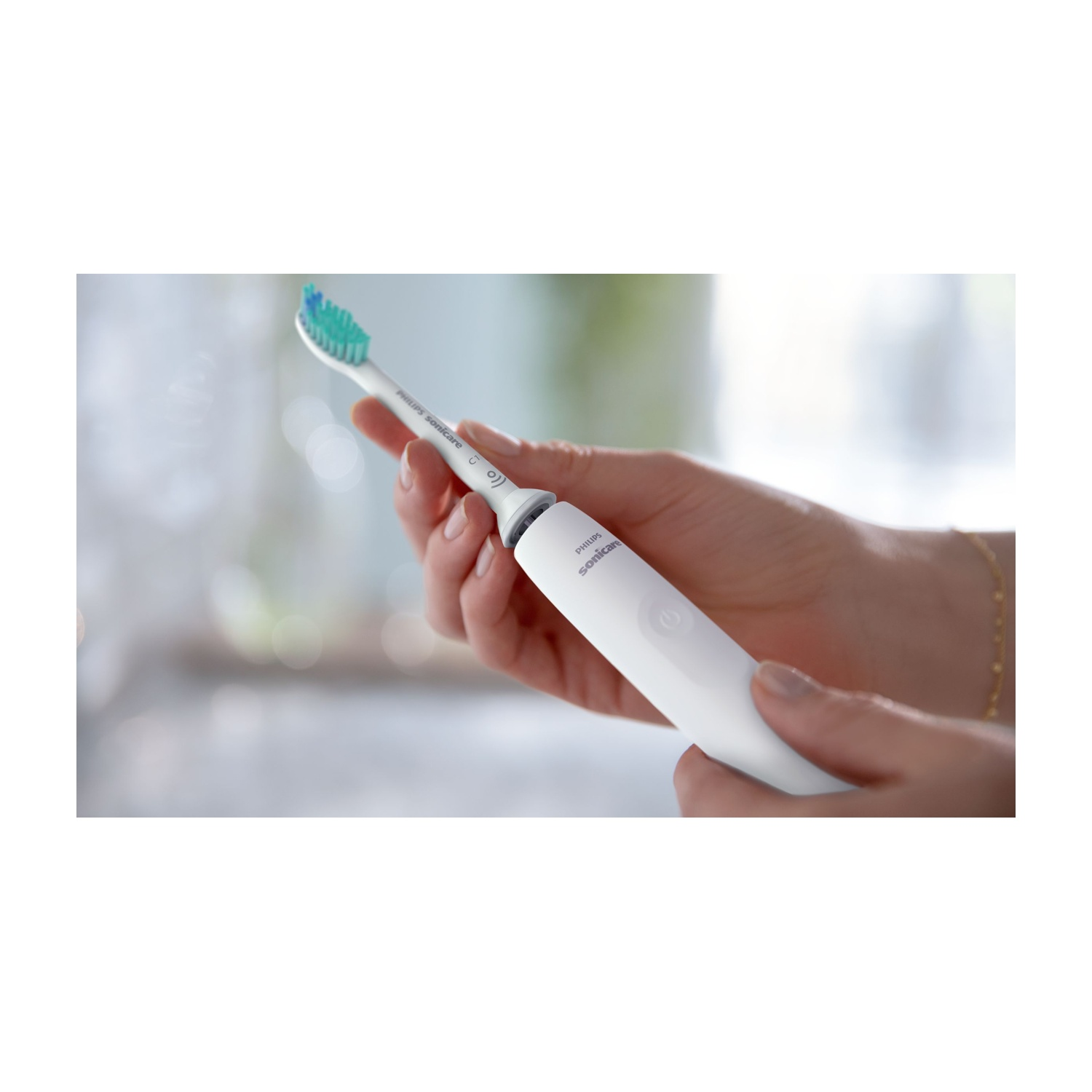 Una persona tiene in mano uno spazzolino elettrico Philips Sonicare bianco. La testina ha setole verdi e blu.