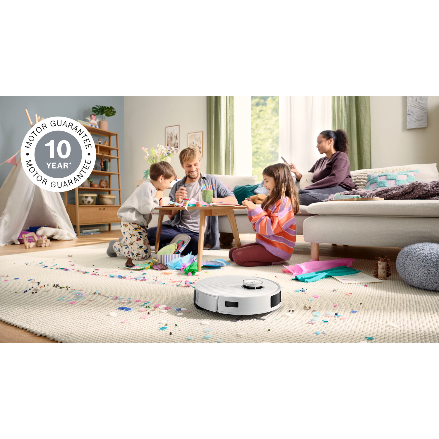 Family crafts with a robot vacuum in the foreground. Children, parents, and a robot vacuum are in a living room.