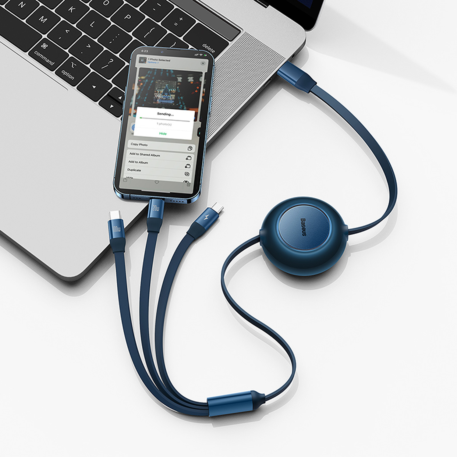 Un teléfono conectado a una laptop por un cable azul. El teléfono muestra una transferencia de archivos. Un dispositivo redondo está al otro extremo del cable.