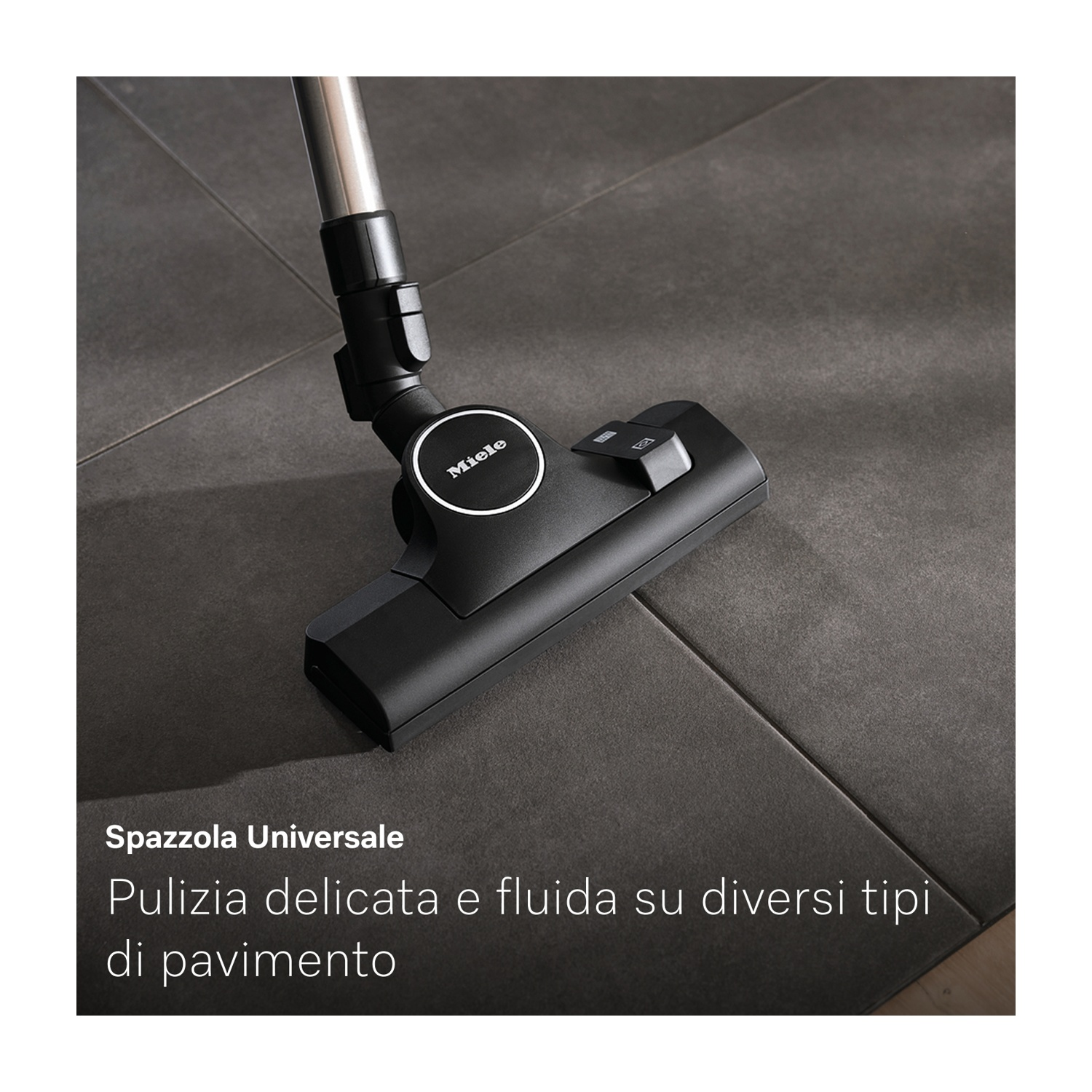 Testa di aspirapolvere Miele nera su piastrelle grigie. L'aspirapolvere è angolato, con un tubo di metallo. Testo: 'Spazzola universale'.