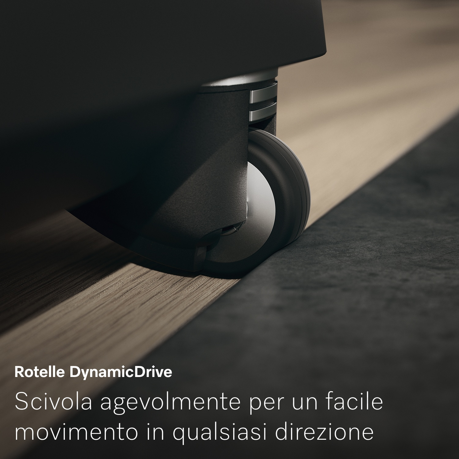 Primo piano di una ruota nera su un pavimento in legno chiaro. Una superficie grigio scuro è accanto alla ruota. Testo: Rotelle DynamicDrive