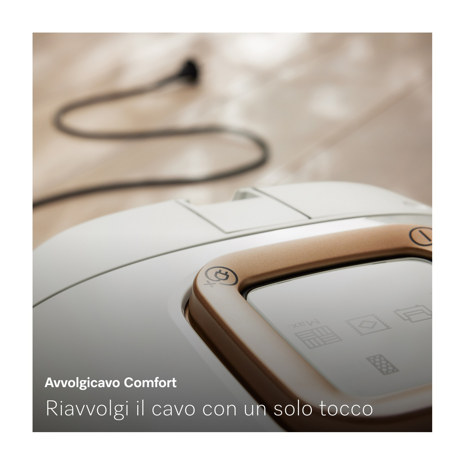 Primo piano di un elettrodomestico bianco e oro con cavo di alimentazione, il testo dice 'Avvolgicavo Comfort, riavvolgi il cavo con un solo tocco'.