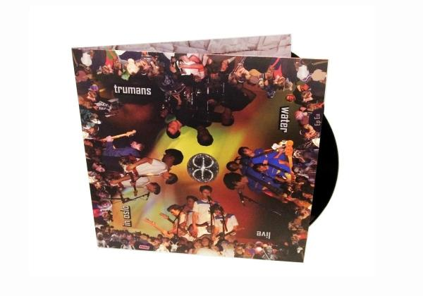 Albumcover: Trumans, 'Water' live in Oslo. Bild zeigt Bandmitglieder und Publikum. Schwarze Schallplatte teilweise sichtbar.