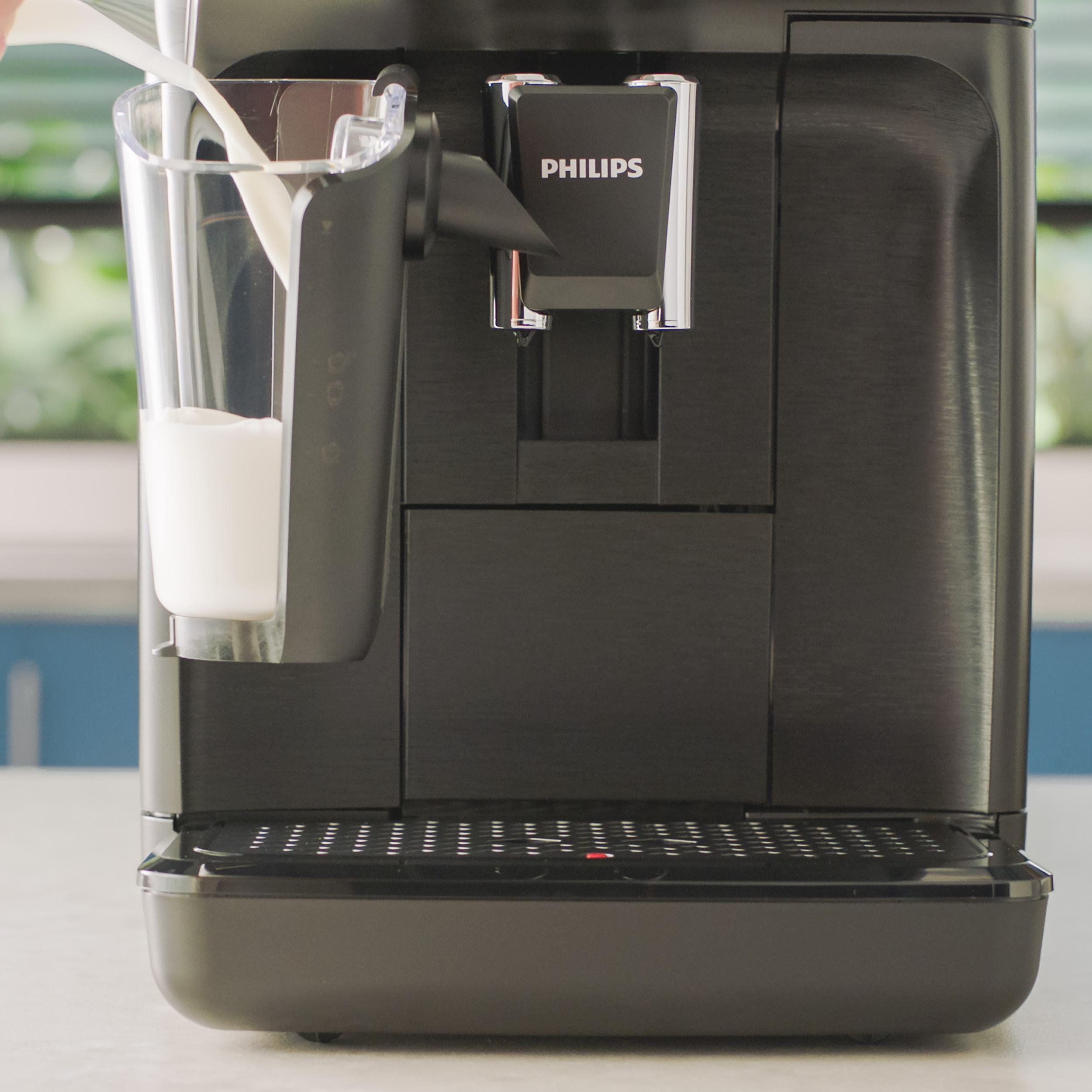 Eine schwarze Philips Kaffeemaschine. Milch wird in ein Glas gegossen. Die Maschine hat einen Wasserauslass.