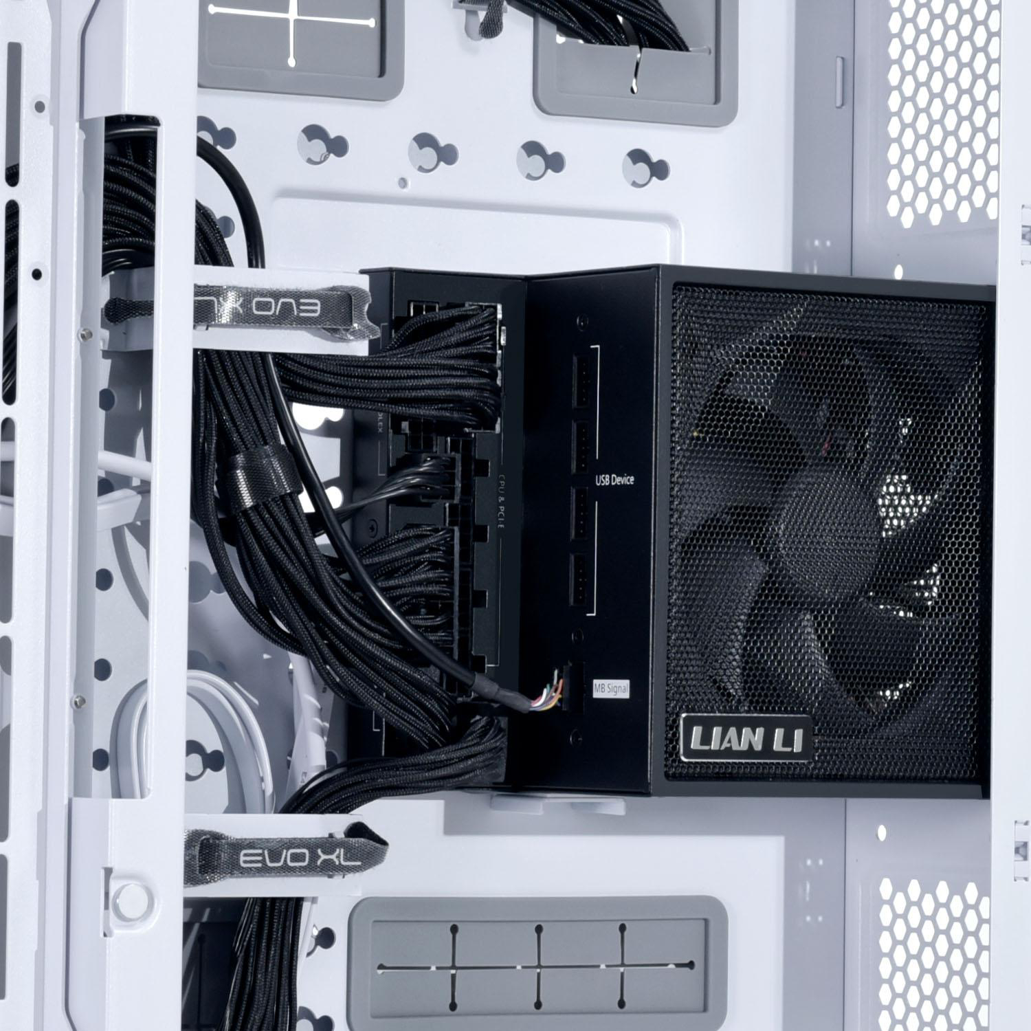 In einem Computergehäuse mit schwarzen Kabeln, einem Netzteil und einem Lüfter. Das Gehäuse ist weiß mit grauen Akzenten und die Marke ist Lian Li.