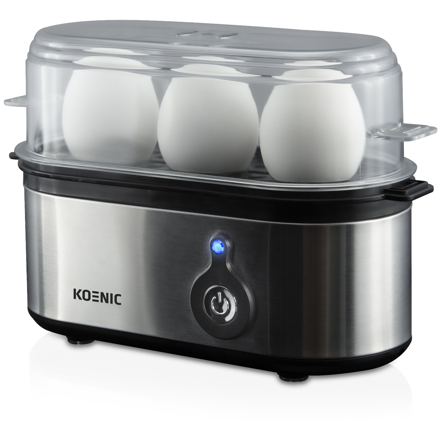 An egg cooker with three white eggs inside. It has a transparent lid and a silver base with a power button.