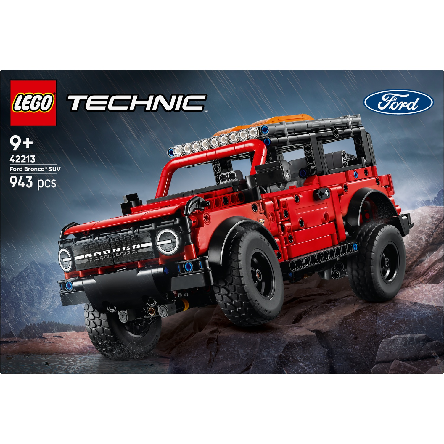 A Lego Technic Ford Bronco SUV model on a rocky surface. The red vehicle has black tires and is set against a blue, rainy background.