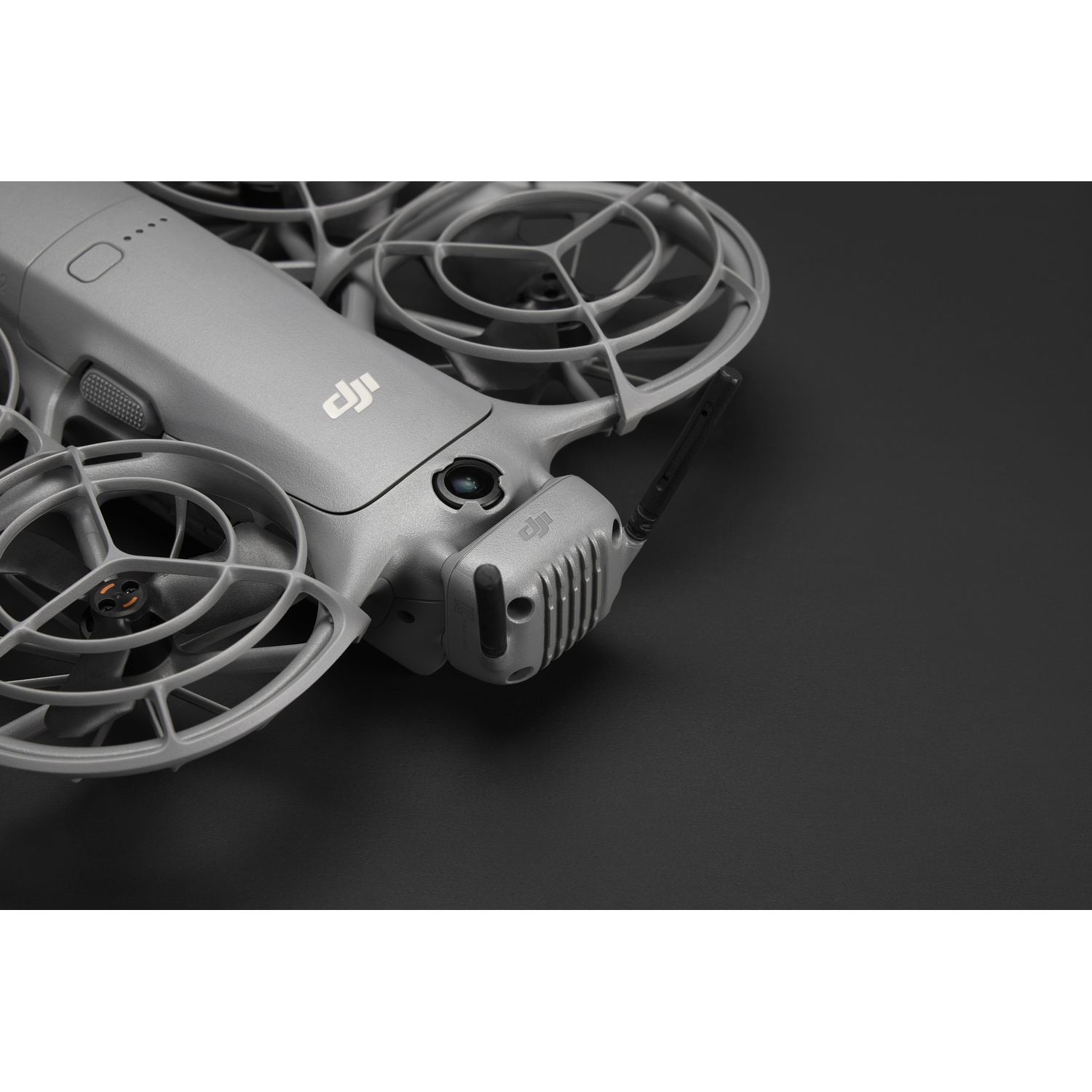 Un drone gris sur une surface noire. On voit les hélices, une caméra et le logo DJI. Le drone est incliné, montrant ses caractéristiques.
