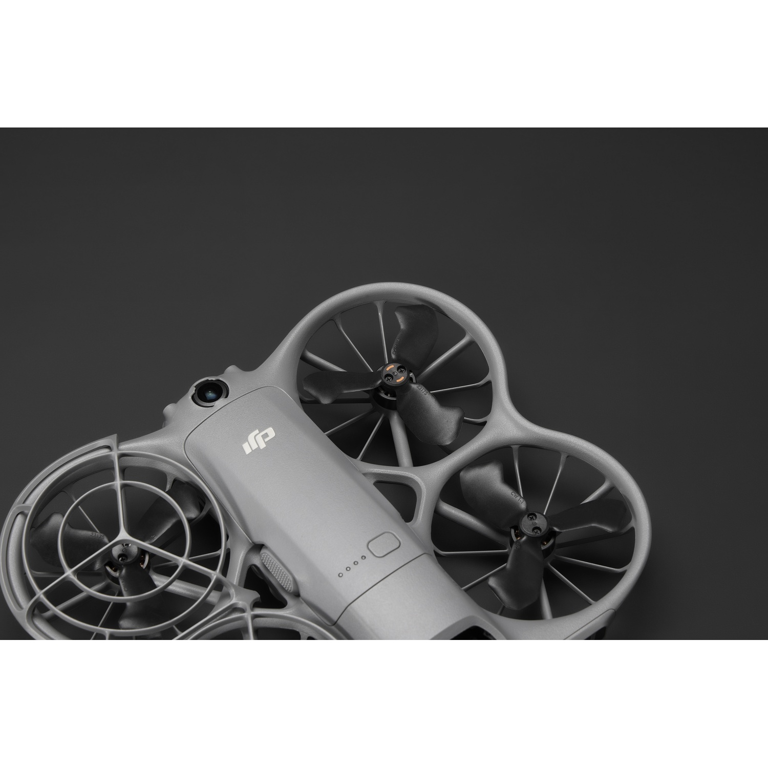 Un drone gris avec quatre hélices. Il possède une caméra et le logo DJI. Le fond est gris foncé.