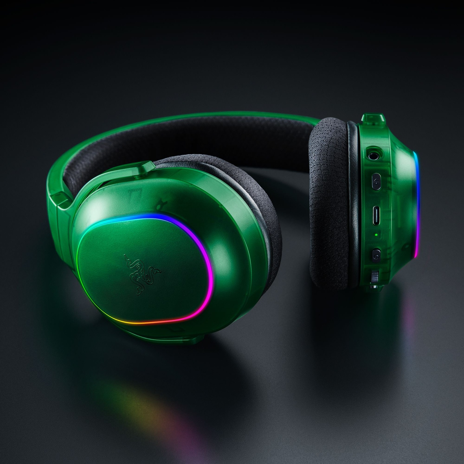 Casque de jeu Razer vert sur une surface sombre. Le casque a des lumières RVB et un rembourrage noir. Le fond est noir.