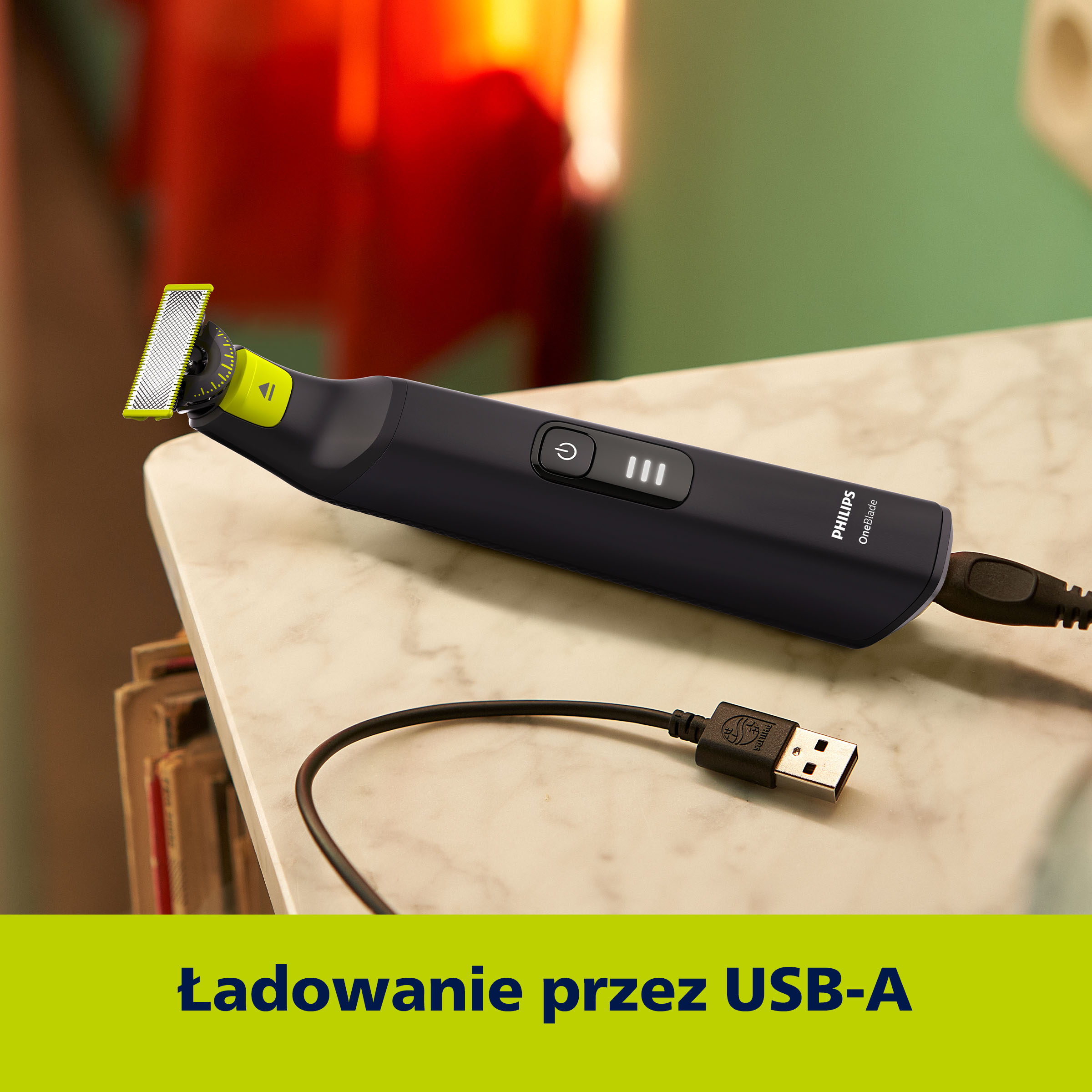 Czarna golarka elektryczna Philips OneBlade z kablem USB, na marmurowym stole. Tło jest rozmyte.