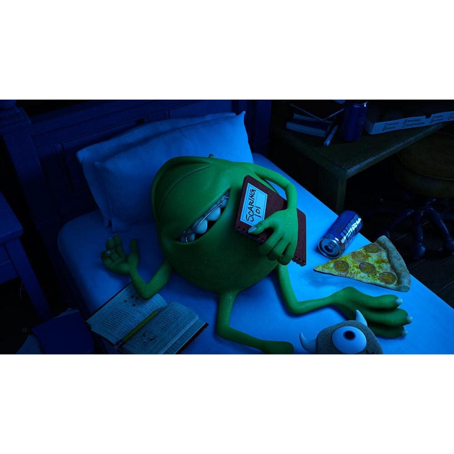 Mike Wazowski in bed, holding a book labeled 'Scaring 101'. Pizza, a soda can and a monster toy are on the bed.