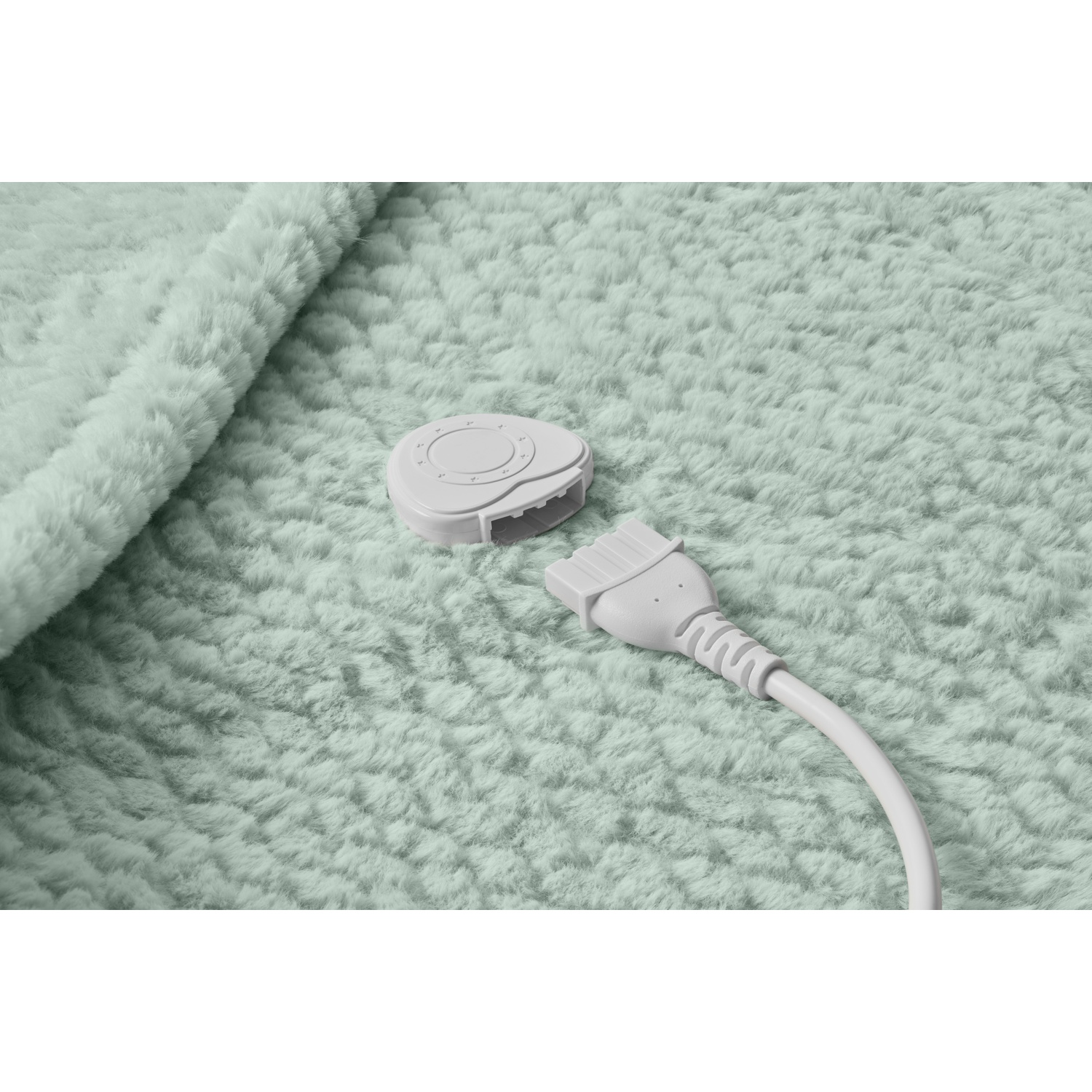 Gros plan d'une couverture moelleuse vert clair avec un connecteur blanc et un cordon d'alimentation.