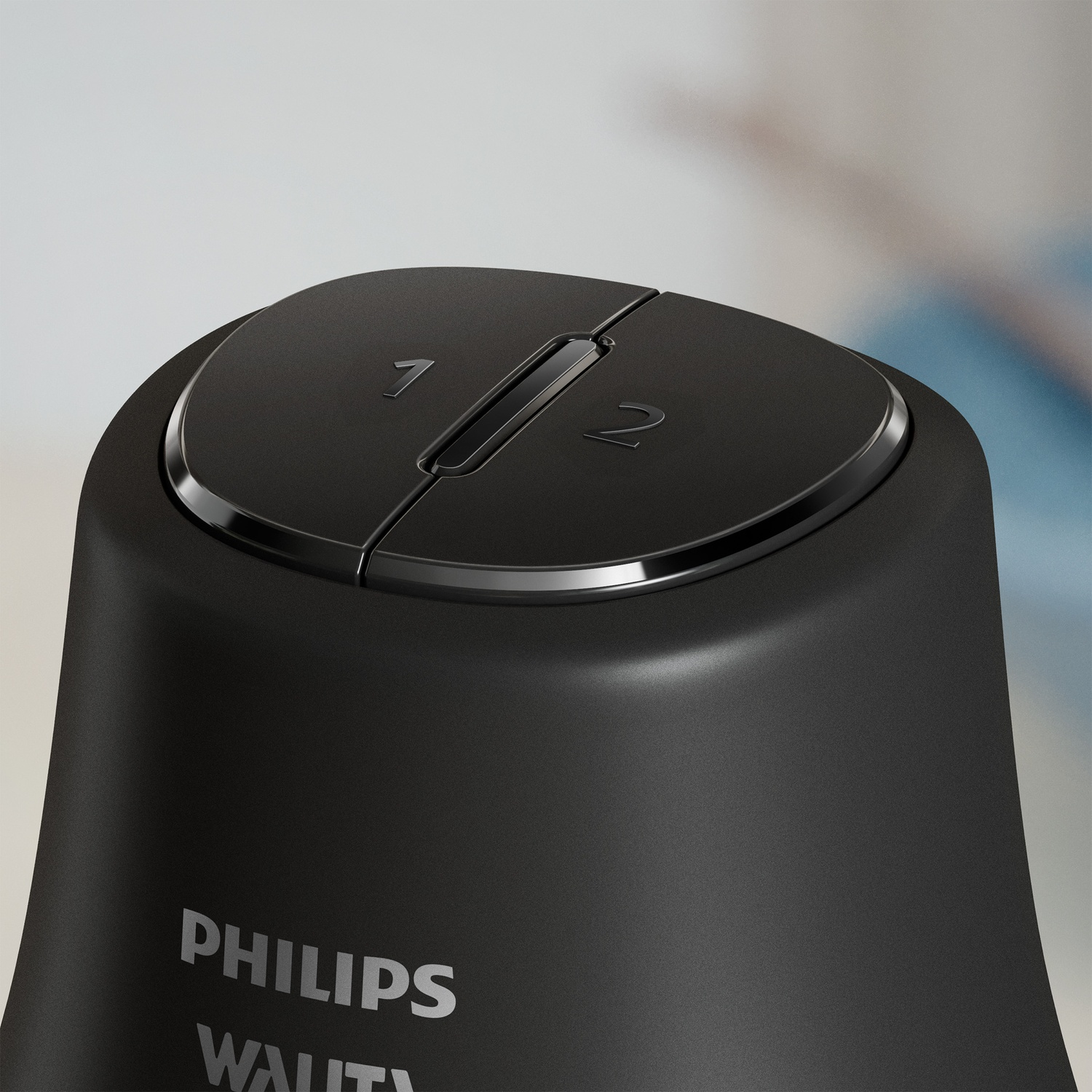 Close-up of a black Philips device. It has a round top with numbers 1 and 2. The brand name is visible on the device.